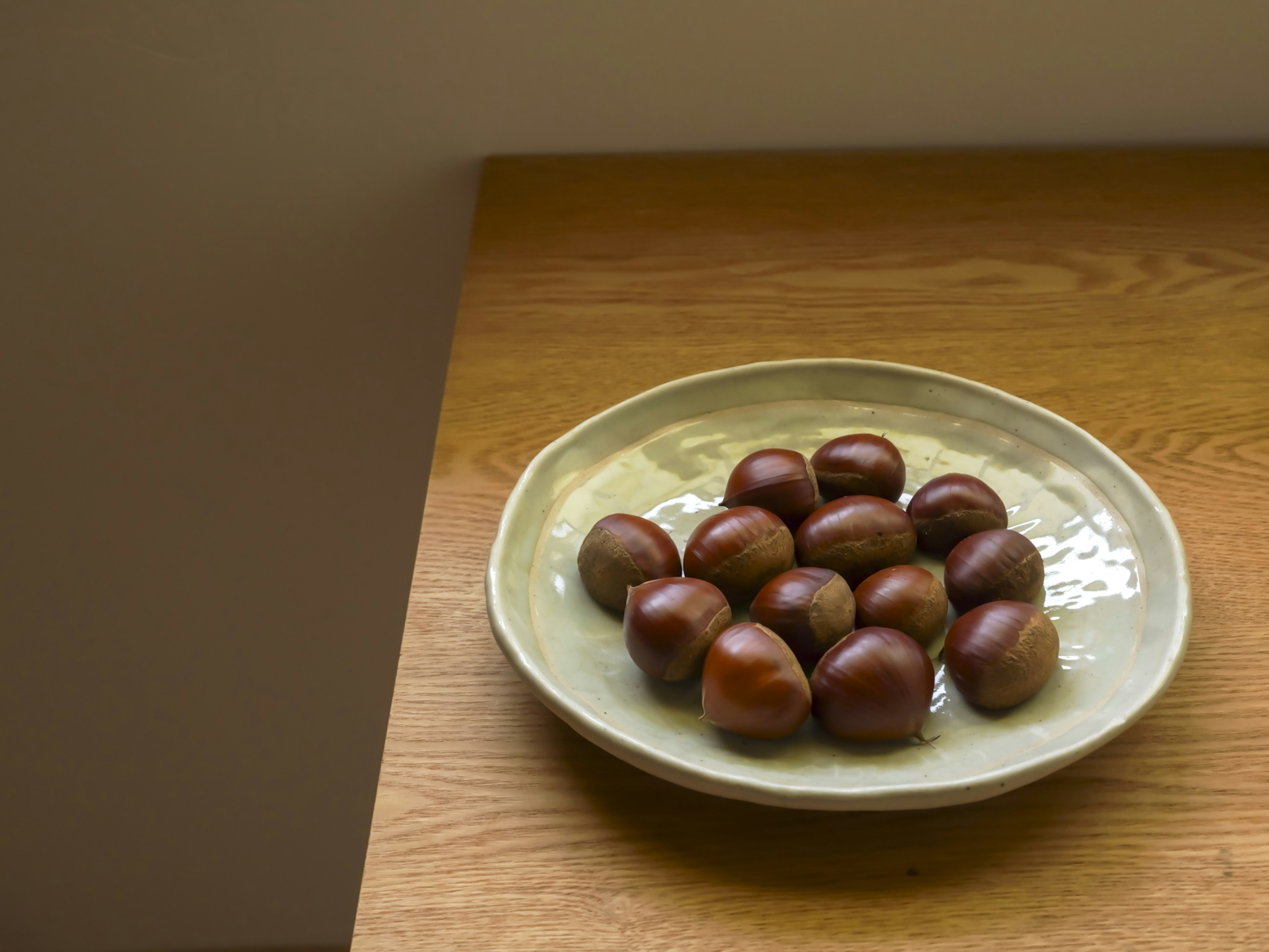 Castagne disposte su un piatto verde su un tavolo di legno