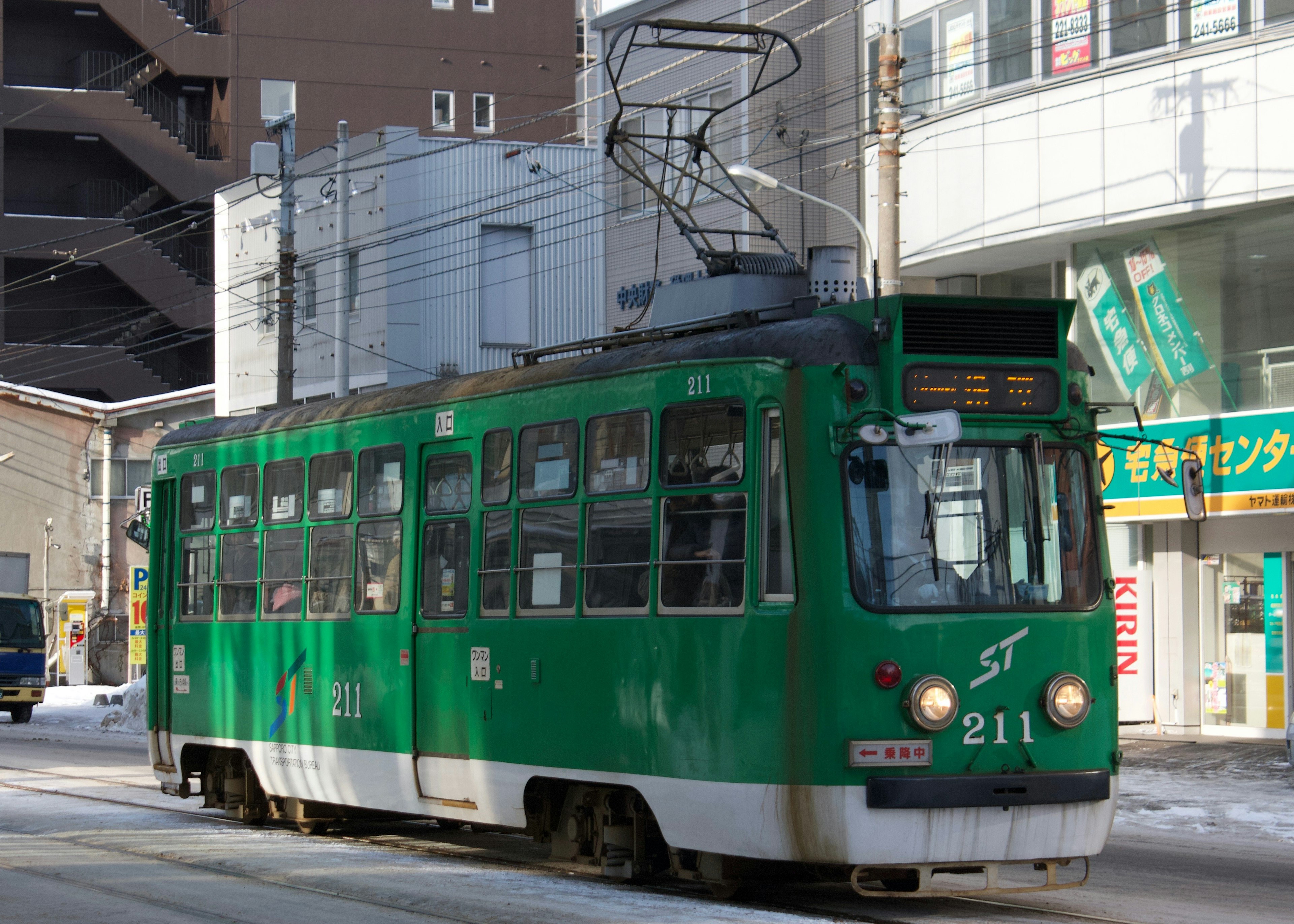 Green streetcar number 211 is running through the city