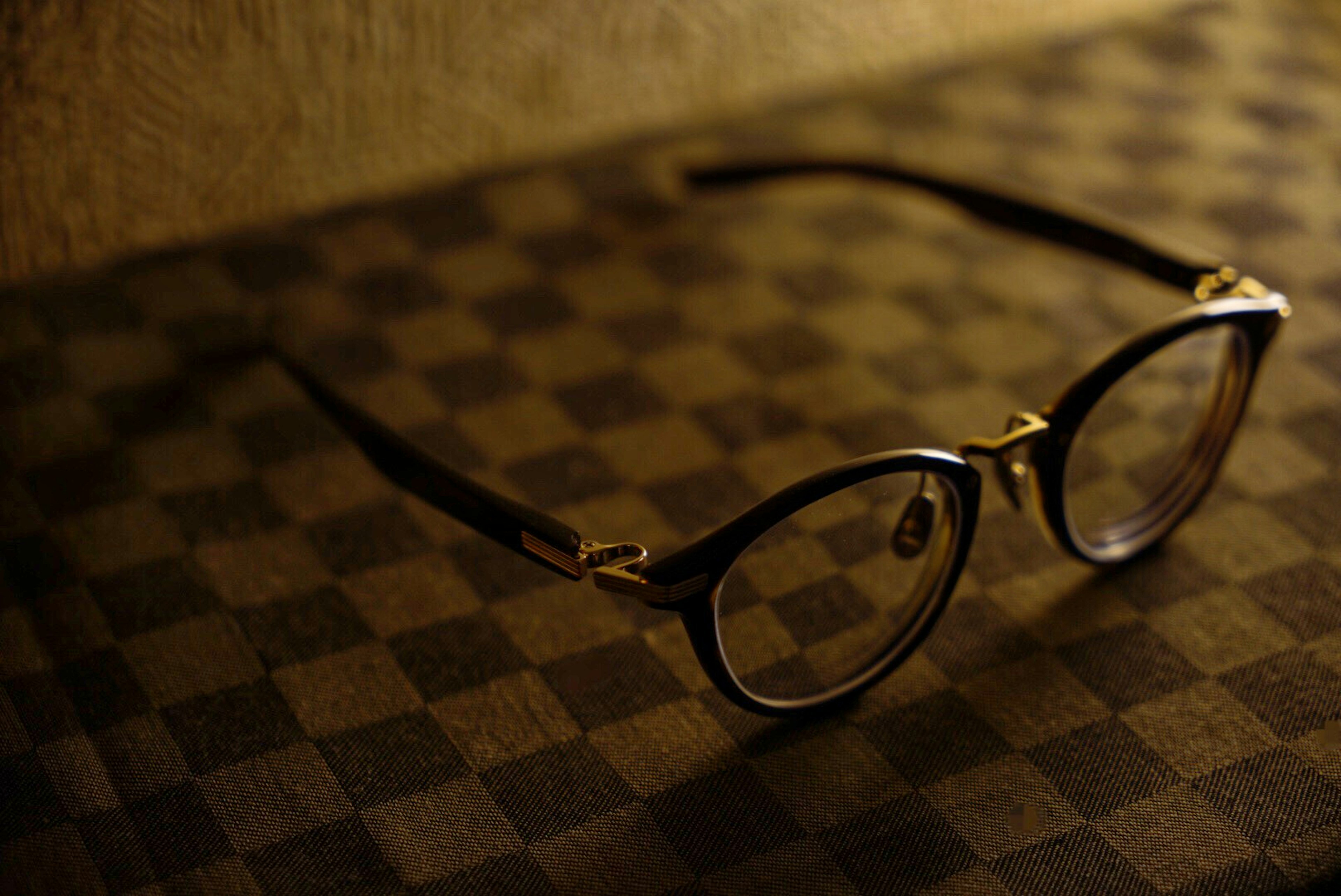 Lunettes à monture noire posées sur une table à carreaux