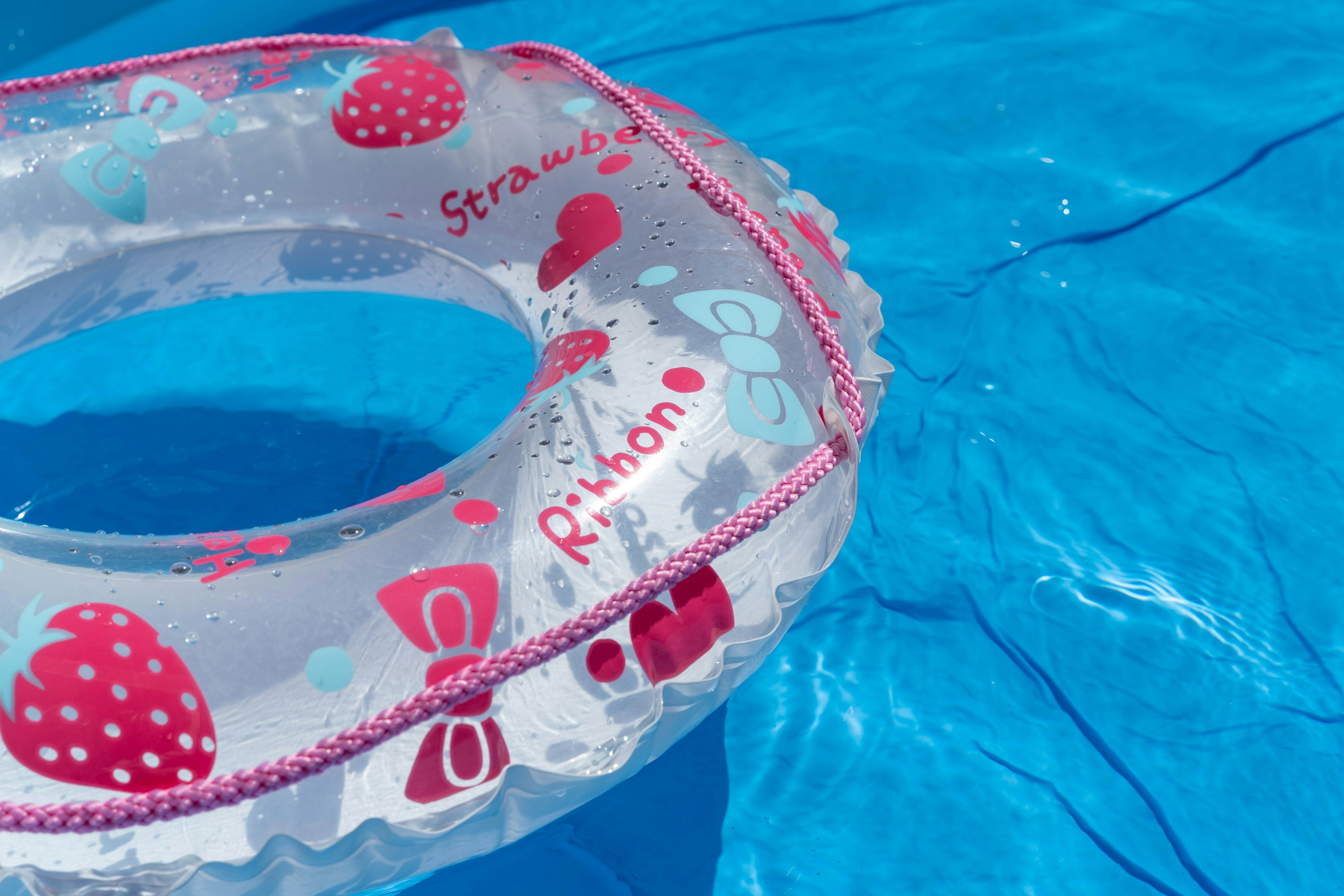 Transparent strawberry-patterned float ring in a swimming pool