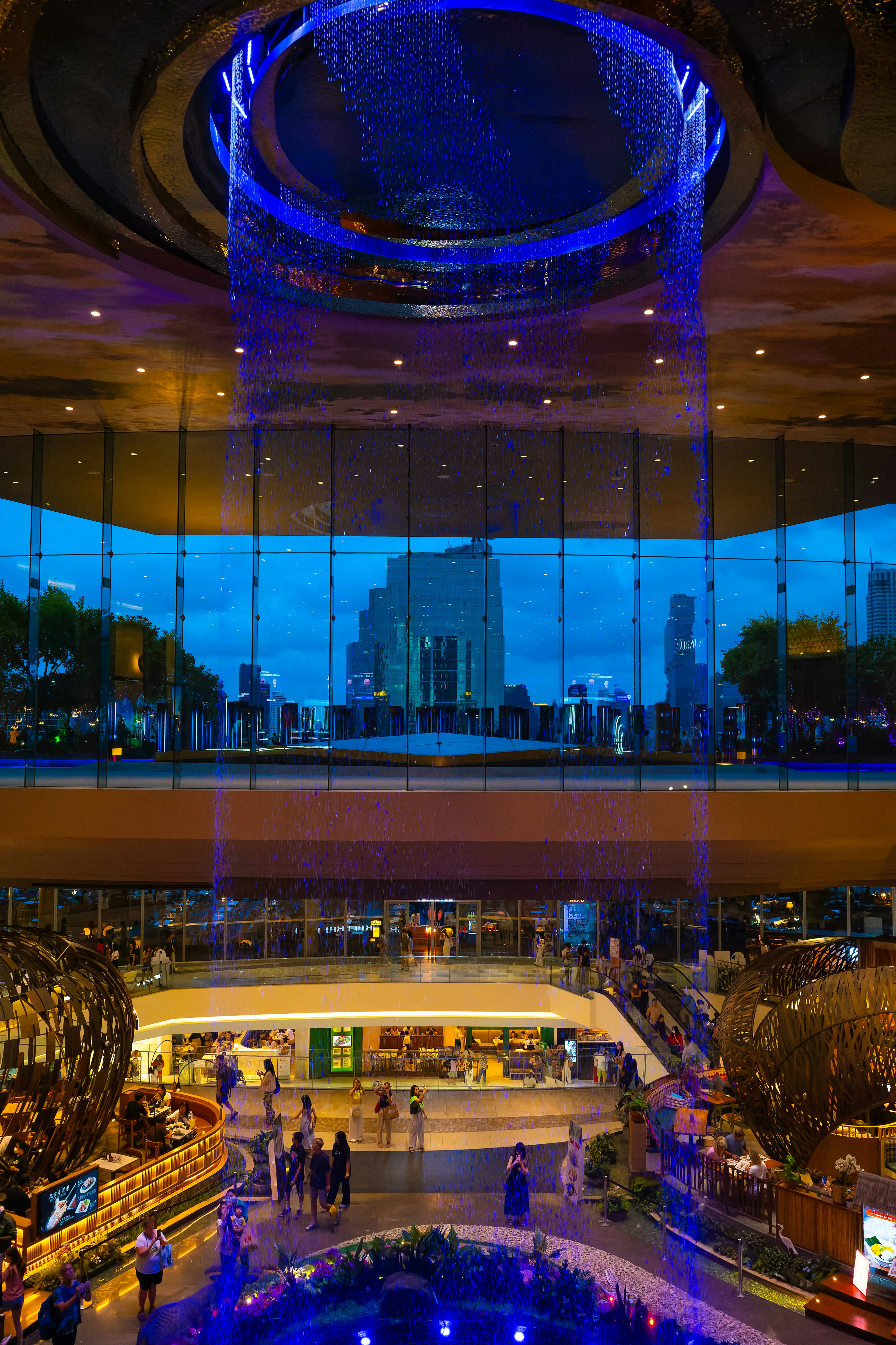 Interior pusat perbelanjaan modern dengan air terjun cahaya biru dan pemandangan kota