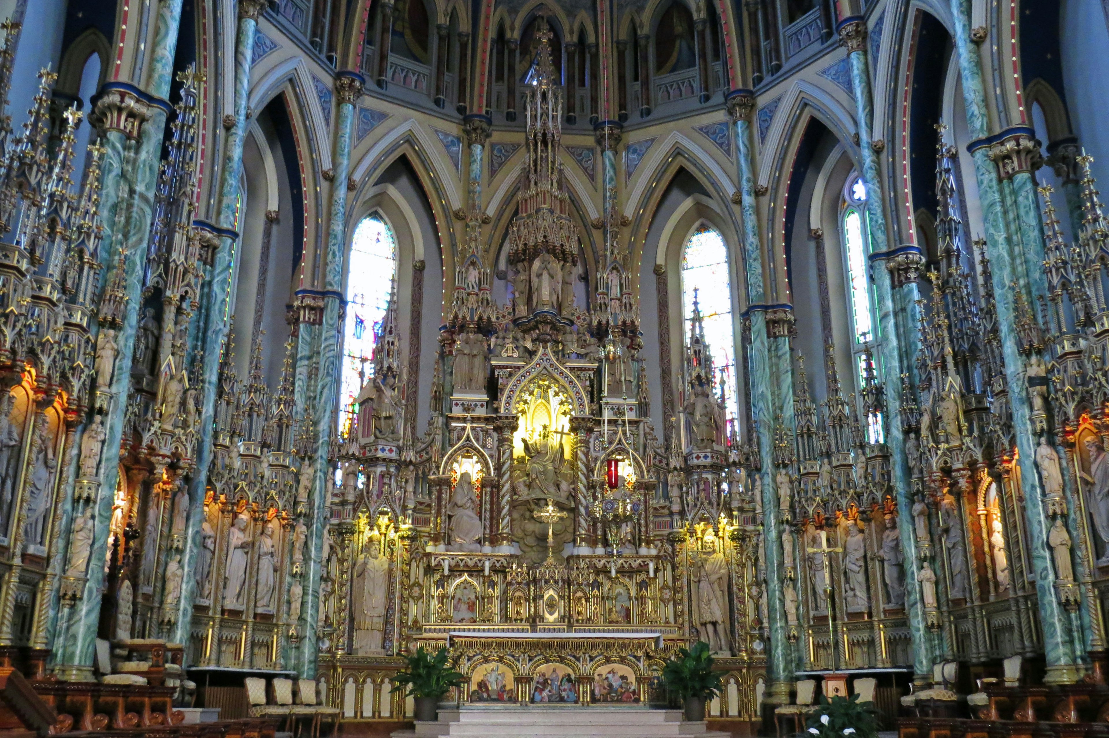 Interior of a beautifully decorated church featuring a grand altar and stained glass windows