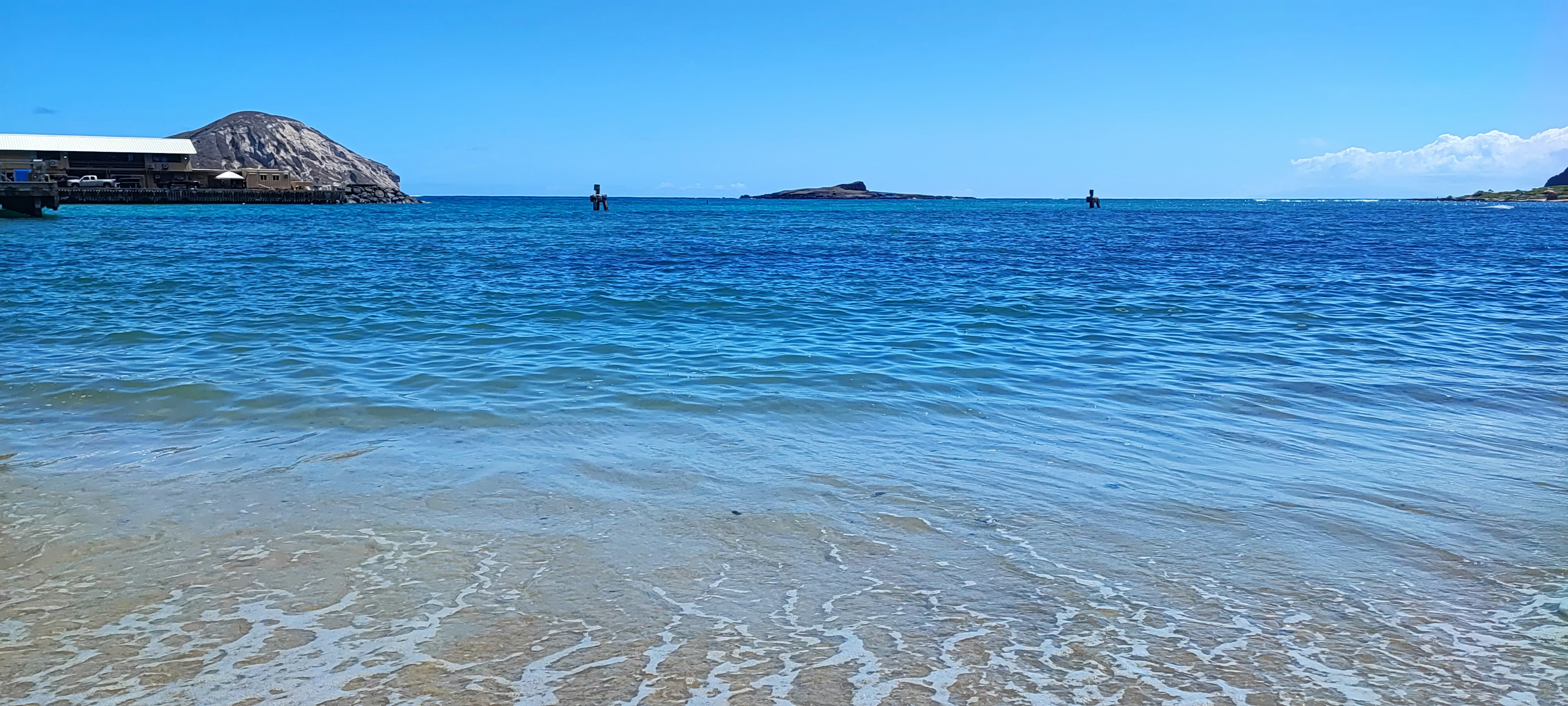 Vista panoramica di una spiaggia con oceano blu e cielo barche che galleggiano su acqua calma