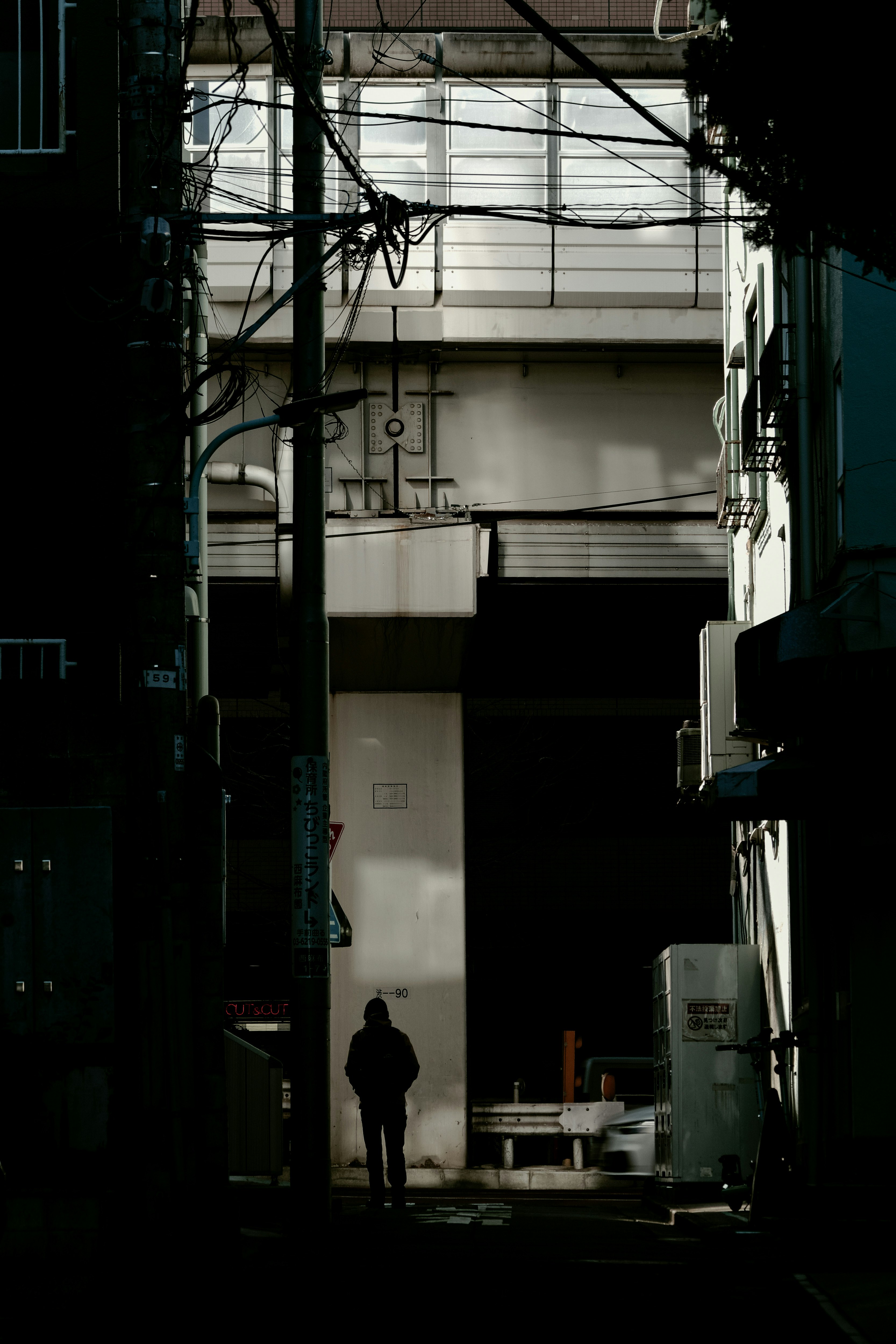Silhouette of a person standing in a dark alley with surrounding buildings