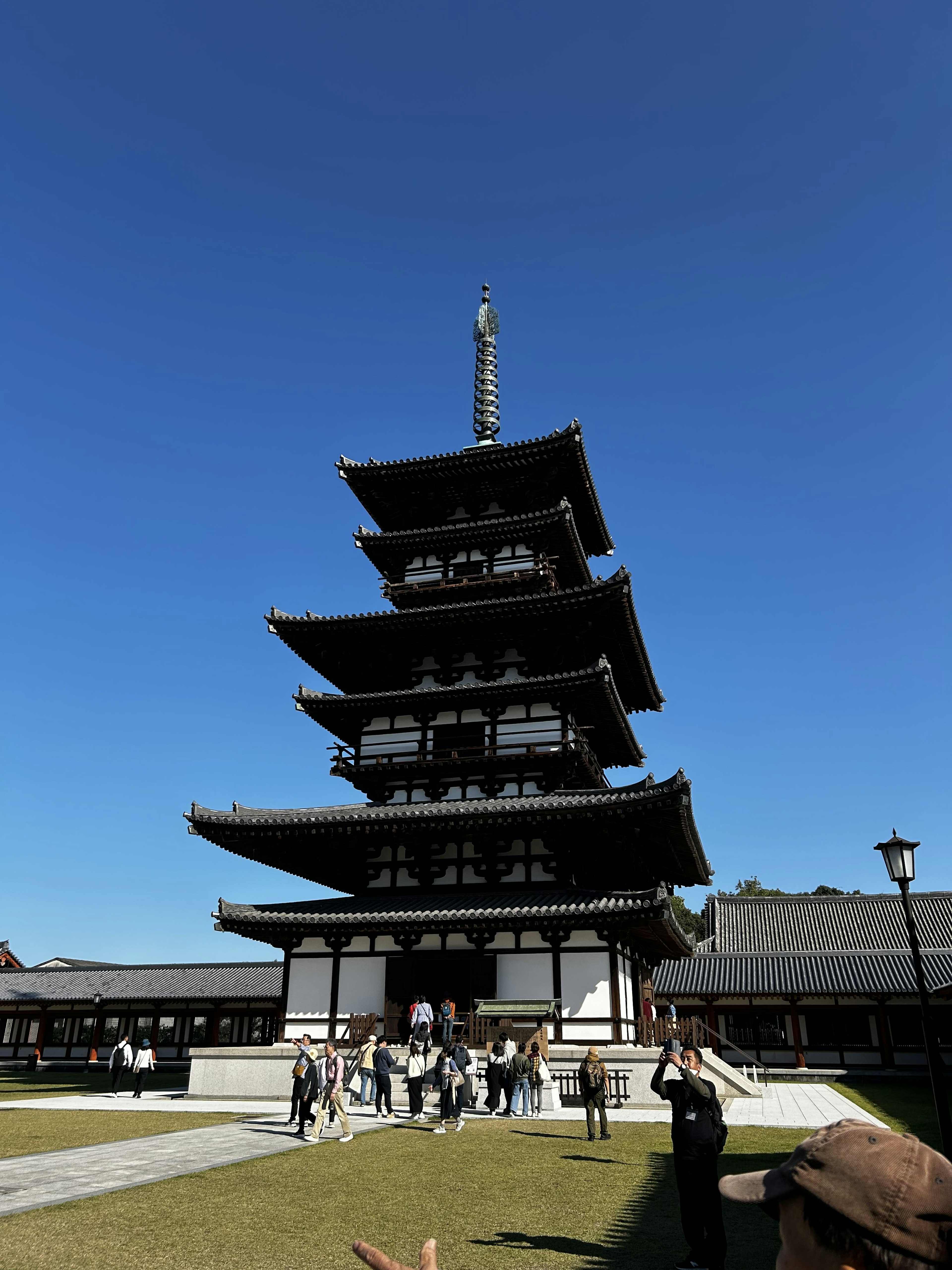 青空の下に立つ五重塔と周囲の観光客