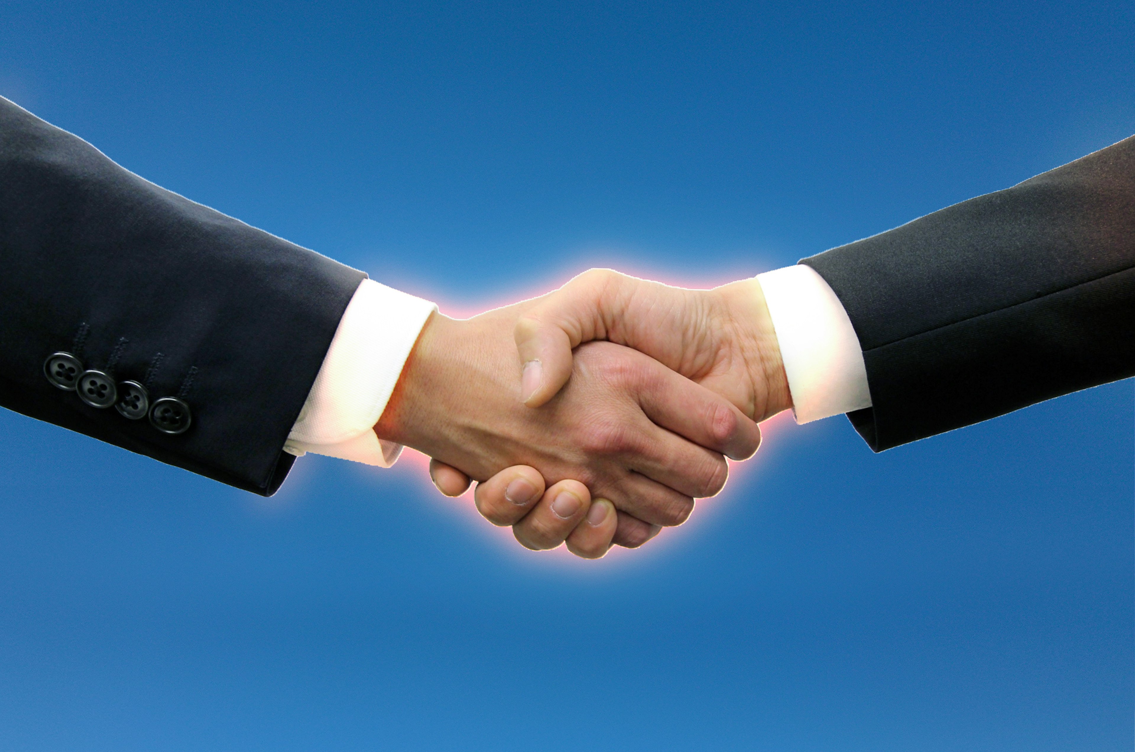 Image highlighting a handshake between businessmen against a blue background