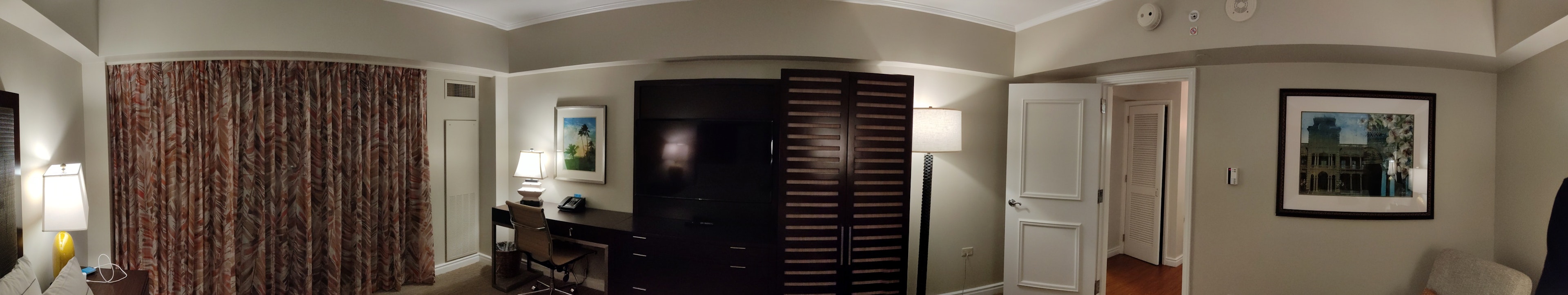 Panoramic view of a hotel room featuring curtains and a desk