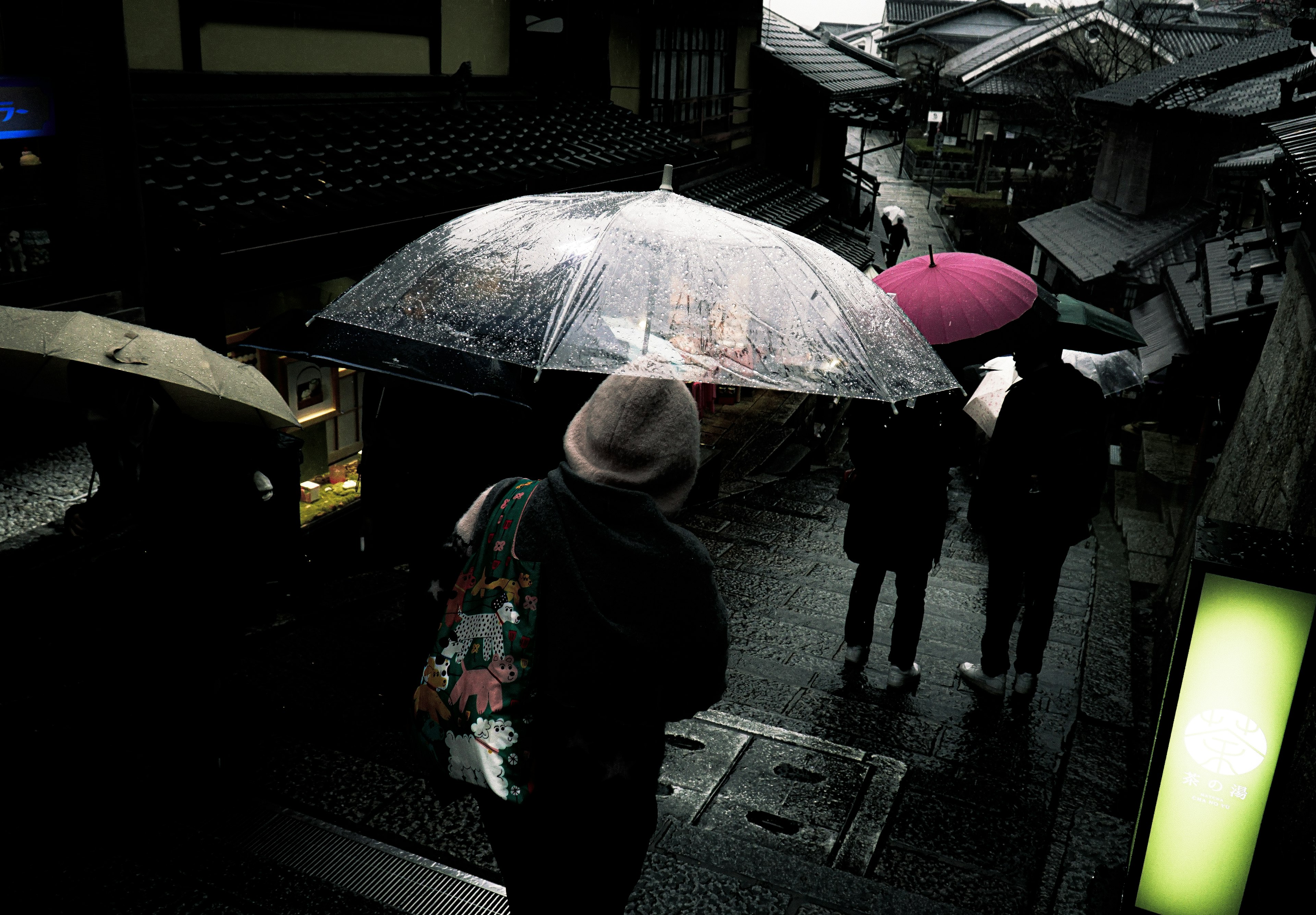 Straßenszene mit Menschen, die bei Regen unter bunten Regenschirmen gehen