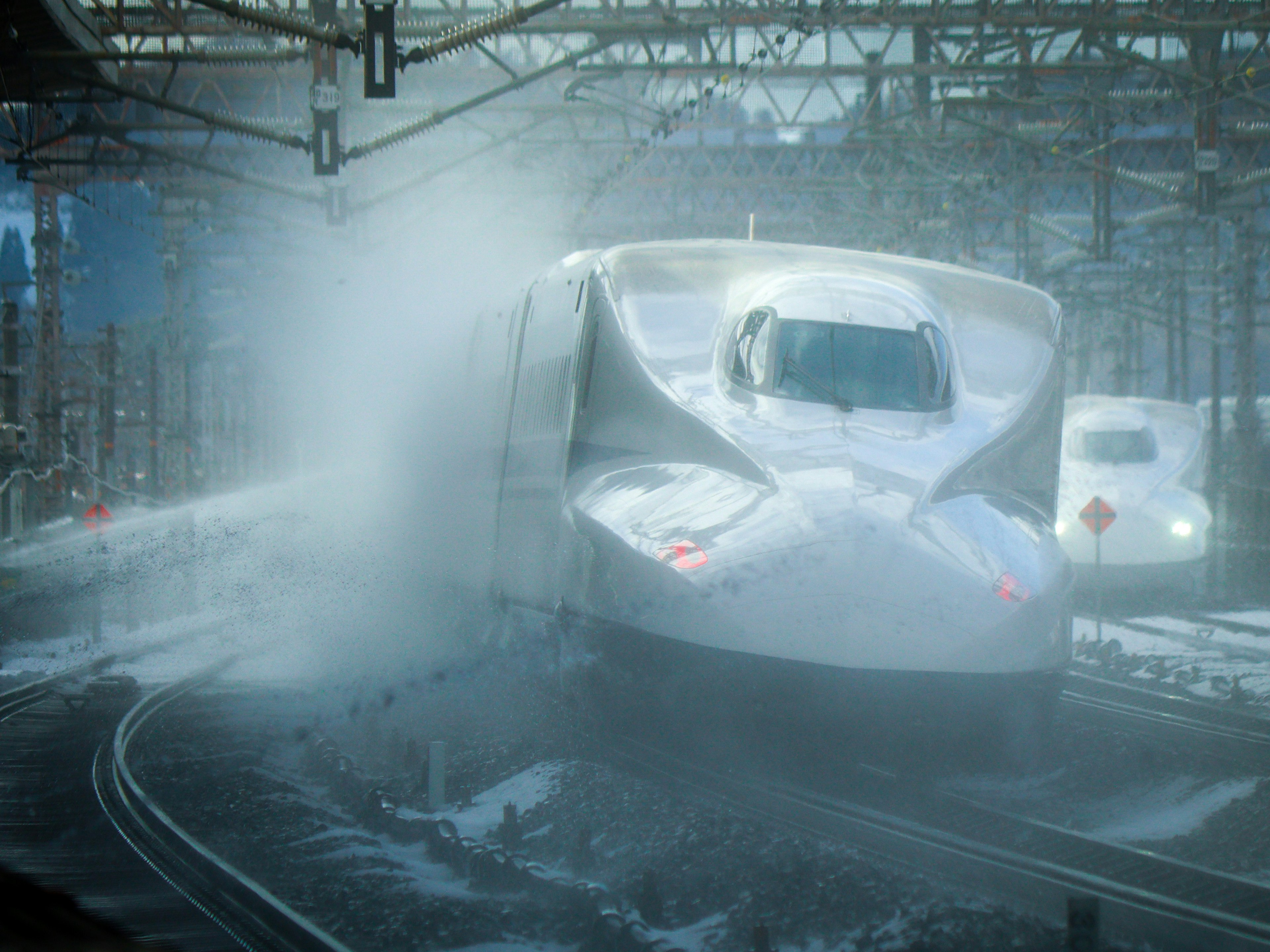 Shinkansen-Zug, der in den Bahnhof einfährt und Schnee spritzt