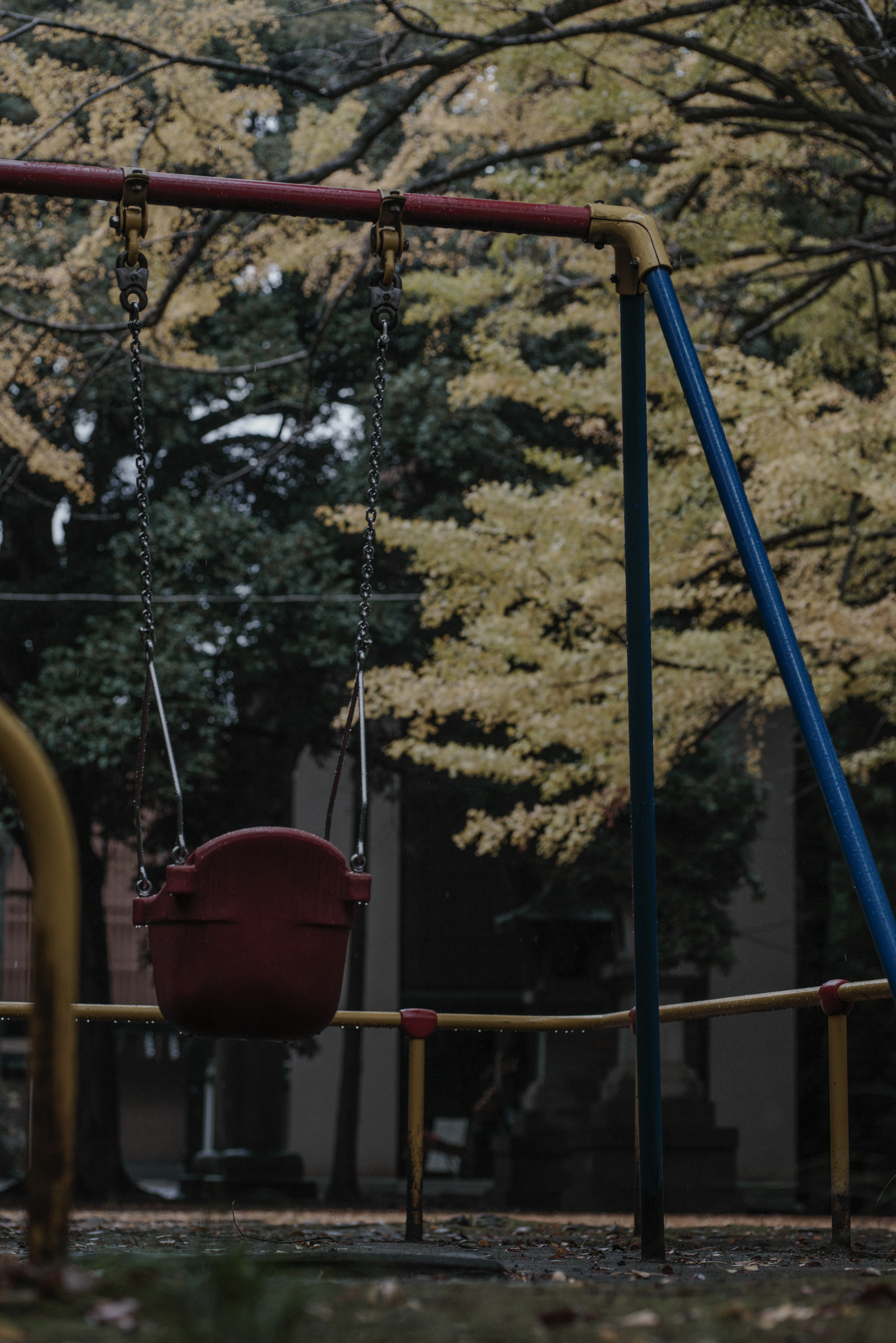 Swing set in a park with autumn trees in the background