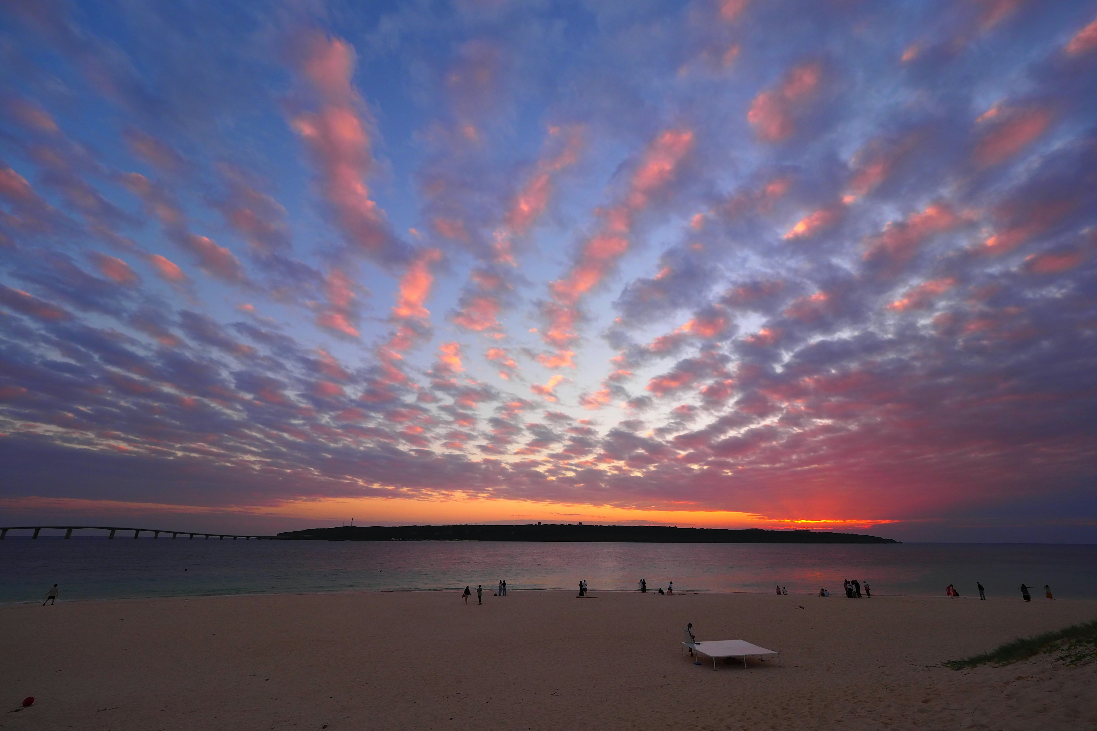 Beautiful beach sunset with colorful clouds spreading across the sky and a distant island visible