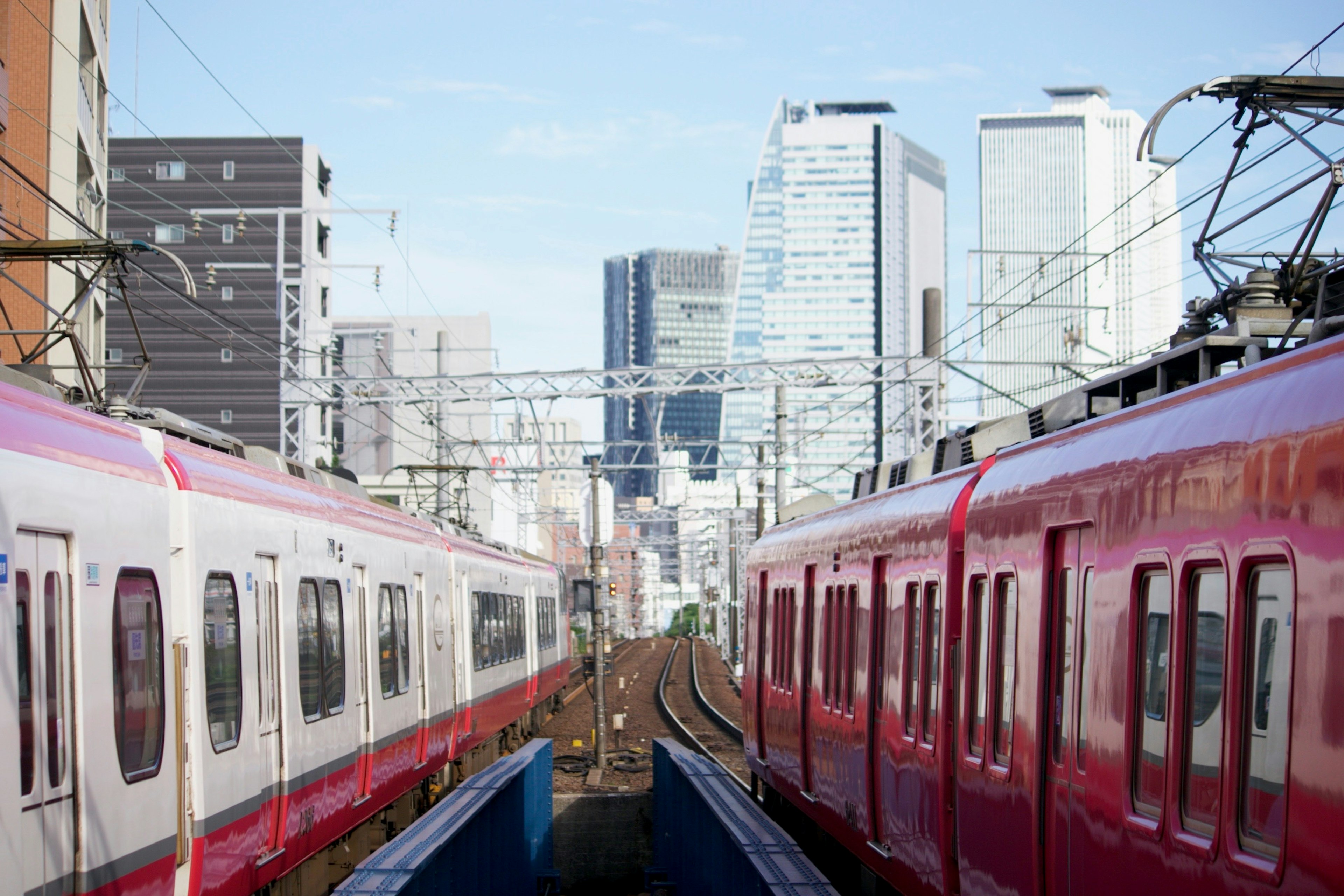 Zwei rote Züge auf Gleisen mit einer Stadtsilhouette im Hintergrund