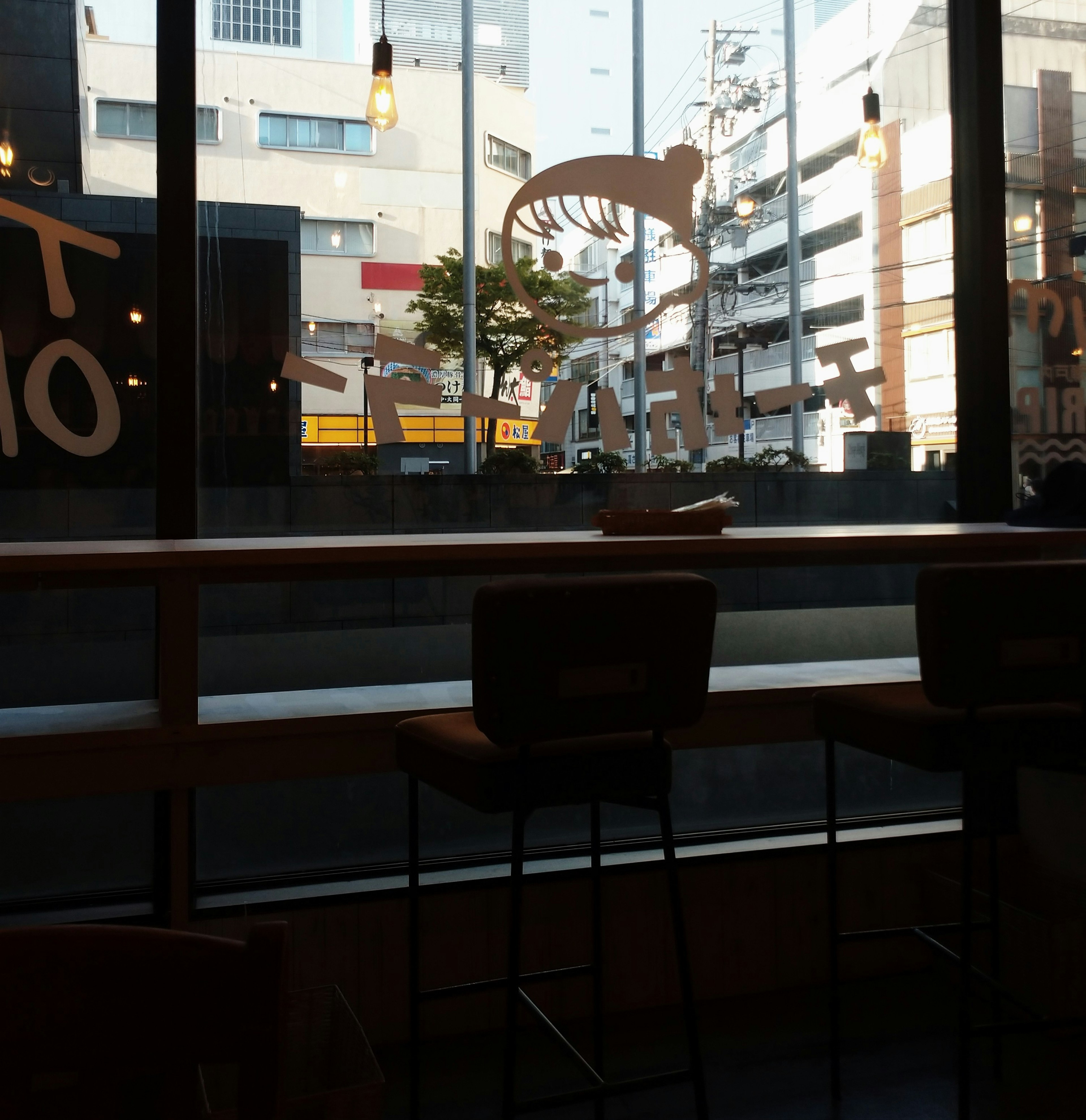 Interior view of a cafe with bar stools and cityscape outside