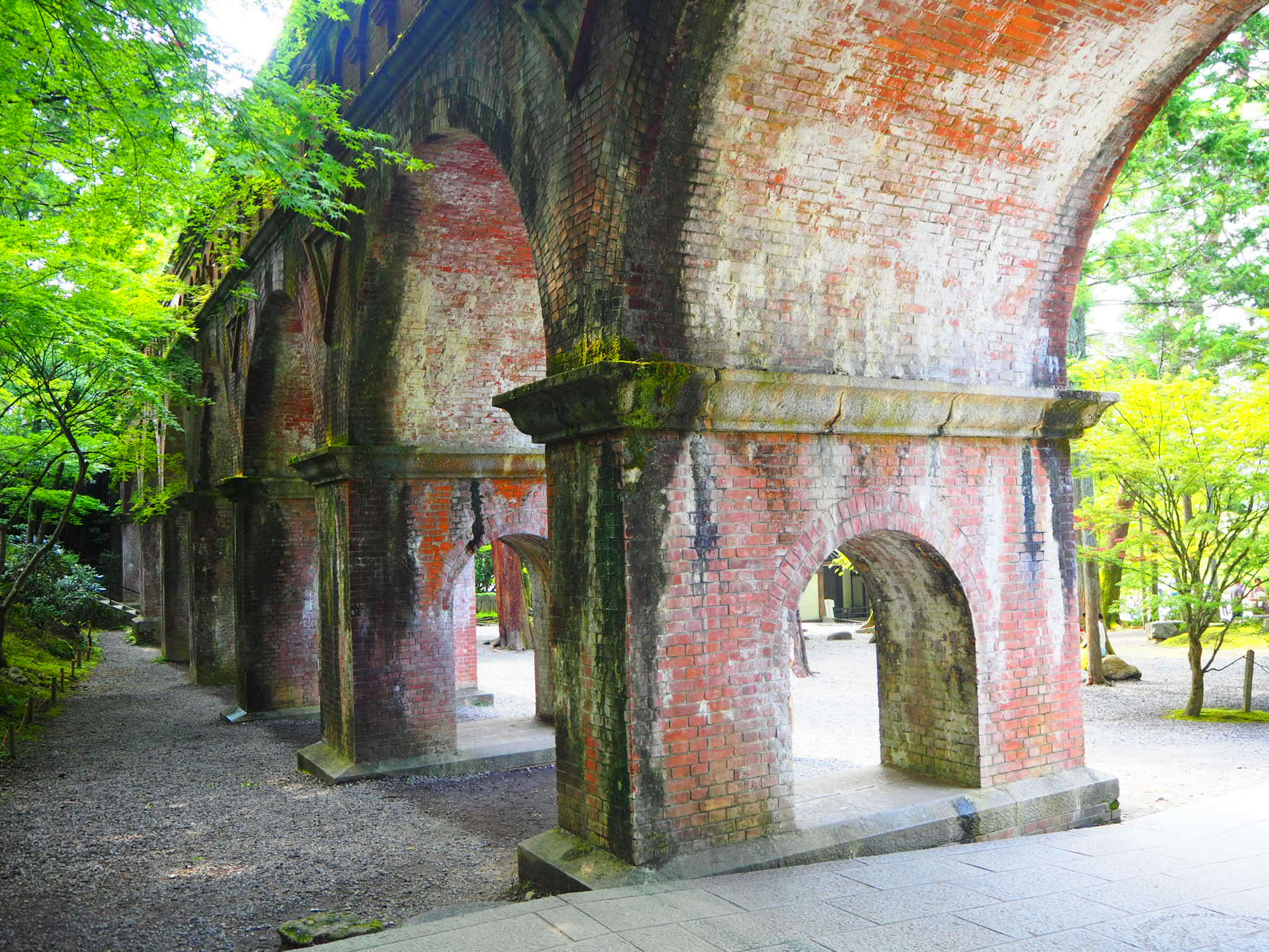 Vista escénica de una antigua estructura de arco de ladrillo rodeada de vegetación