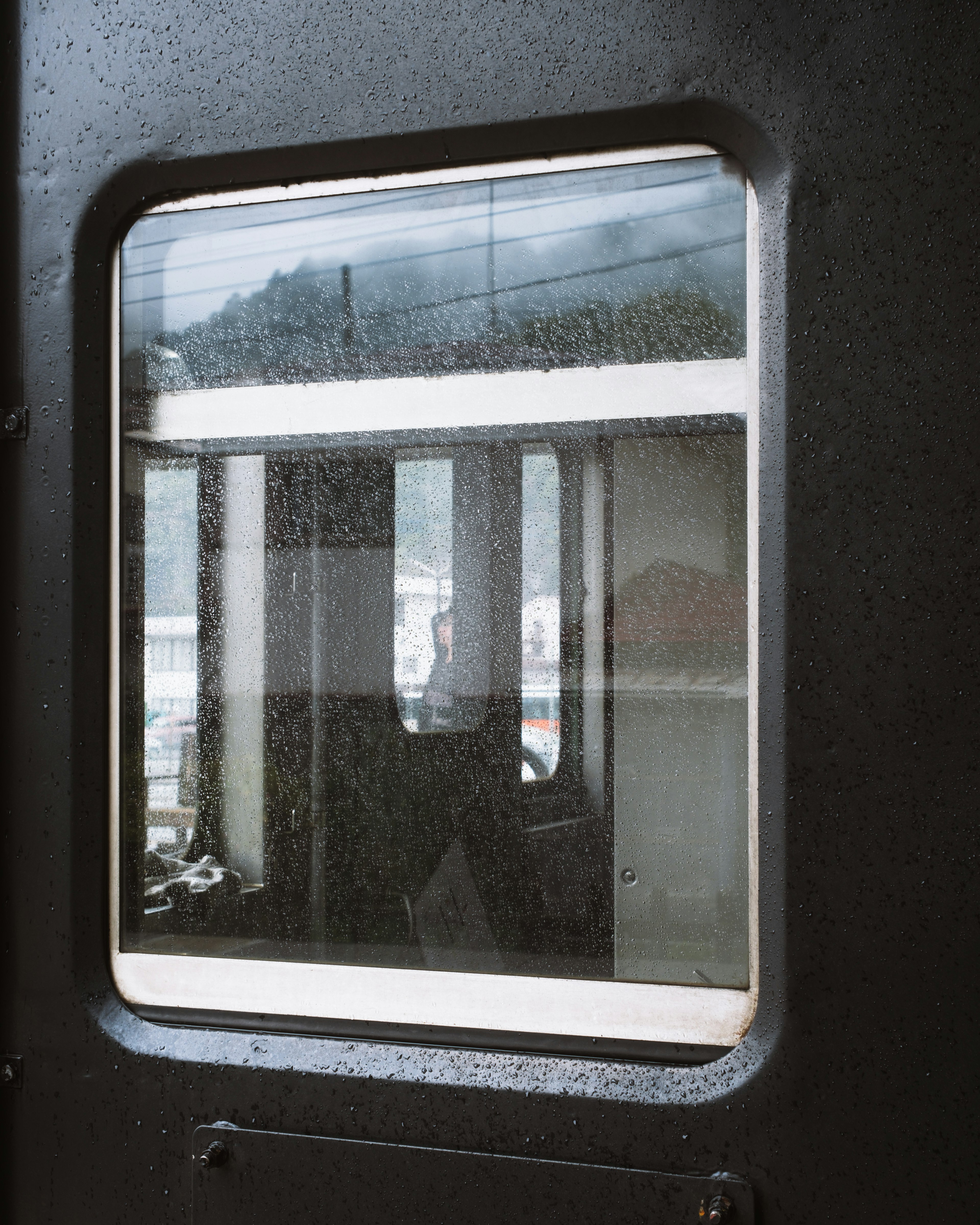 View through a train window showing interior details and raindrops