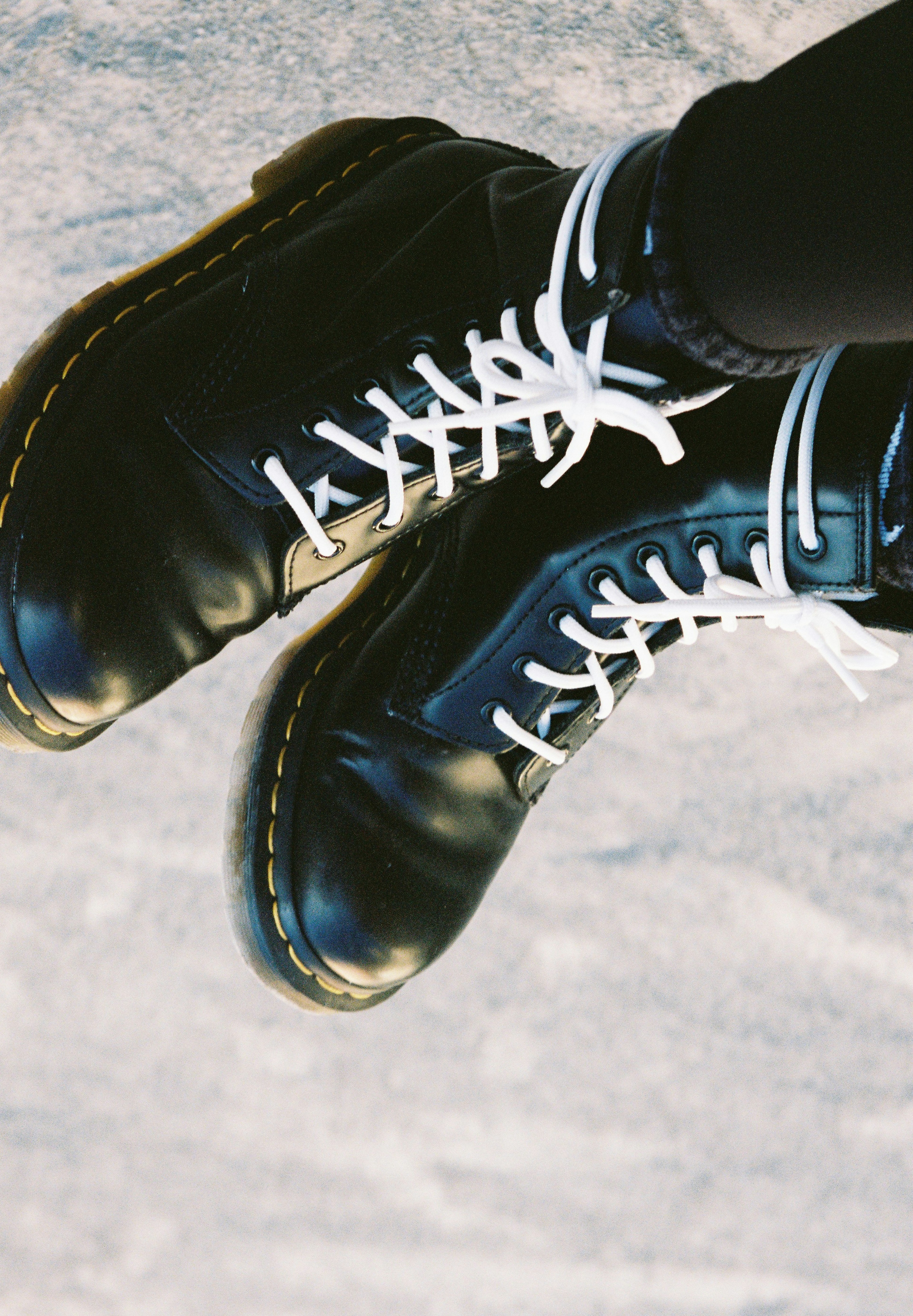 Close-up of black boots with white laces on a textured surface