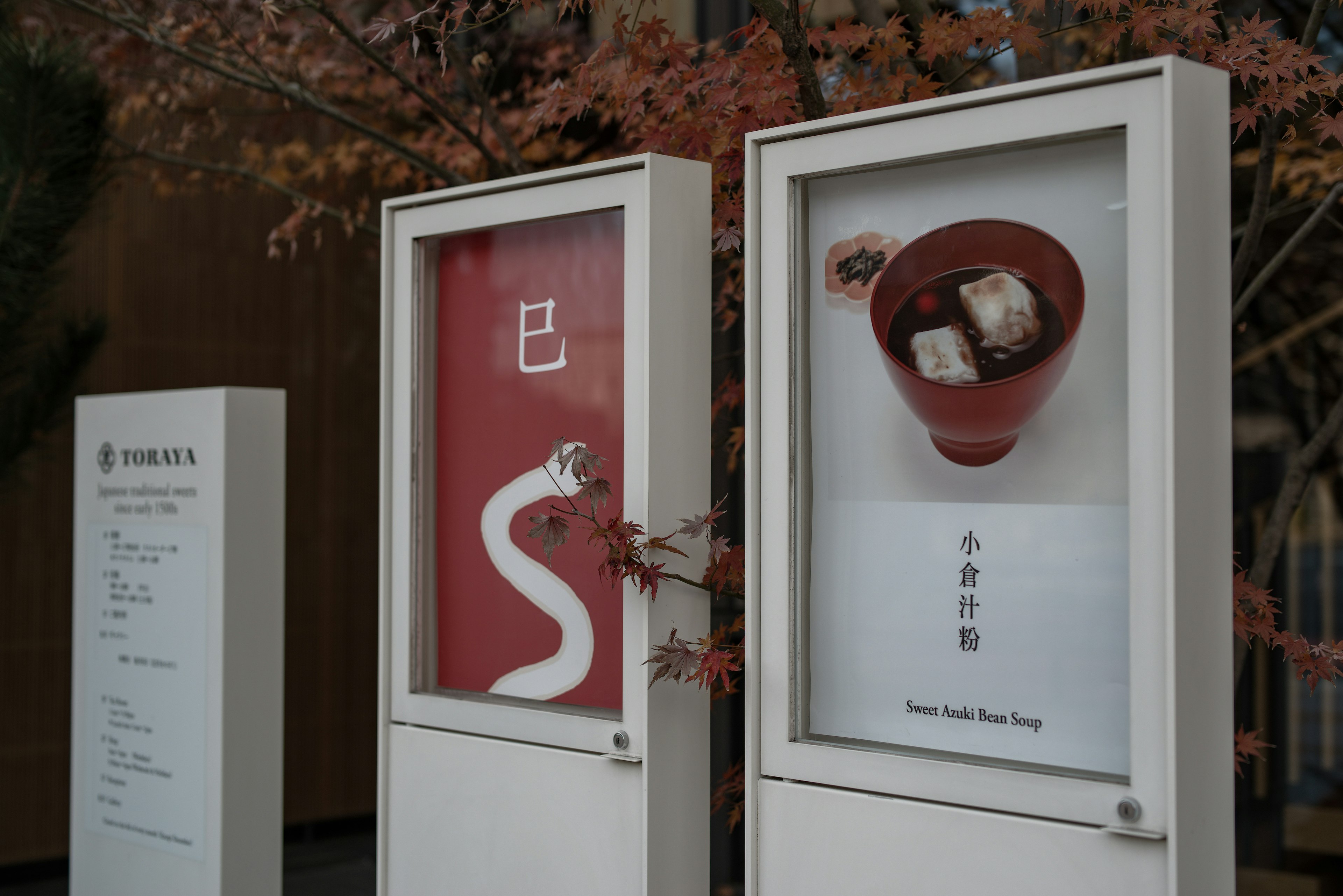 Signage featuring a red background with white text and a brown bowl with food