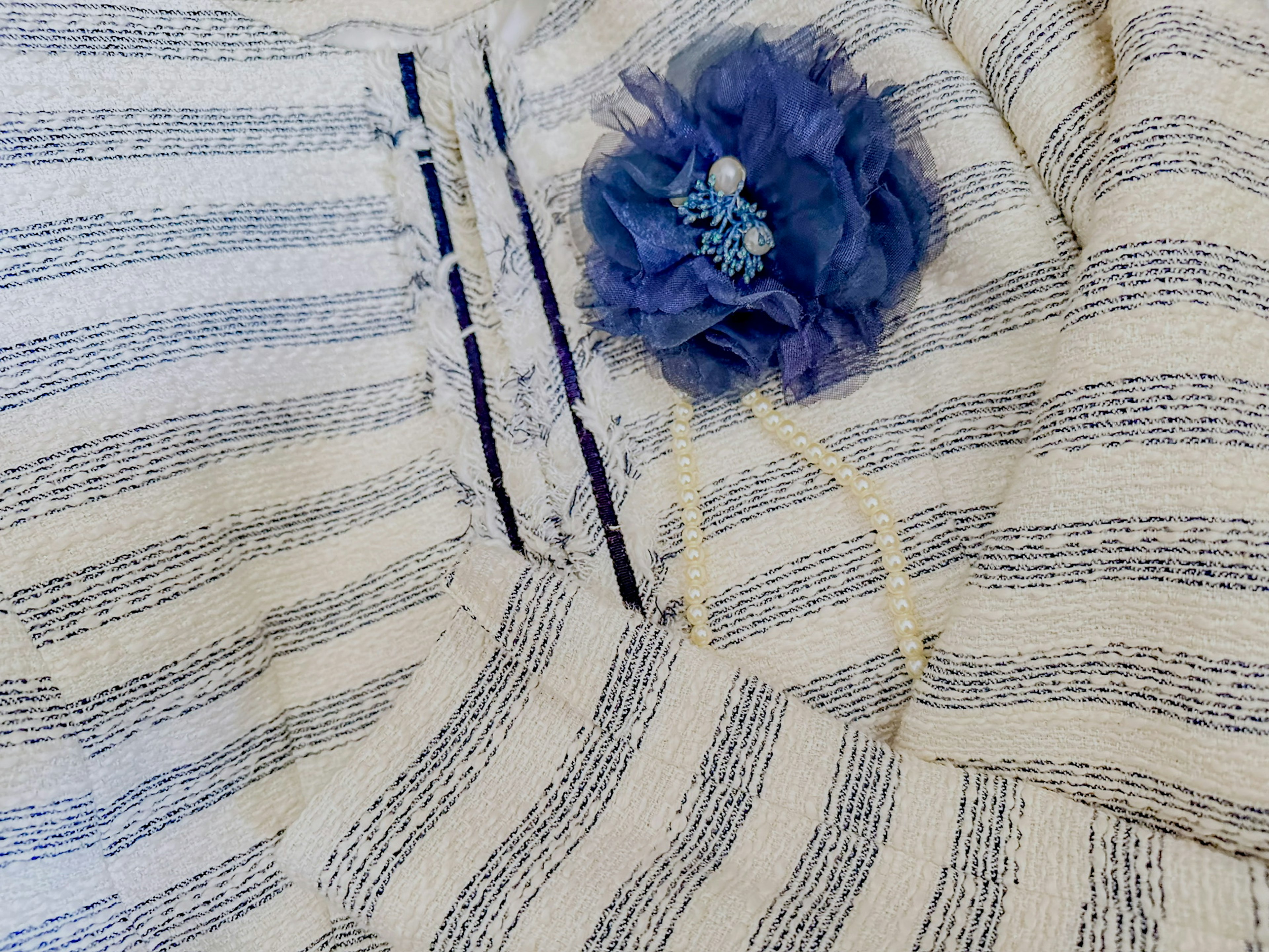 White and blue striped fabric with a blue flower decoration