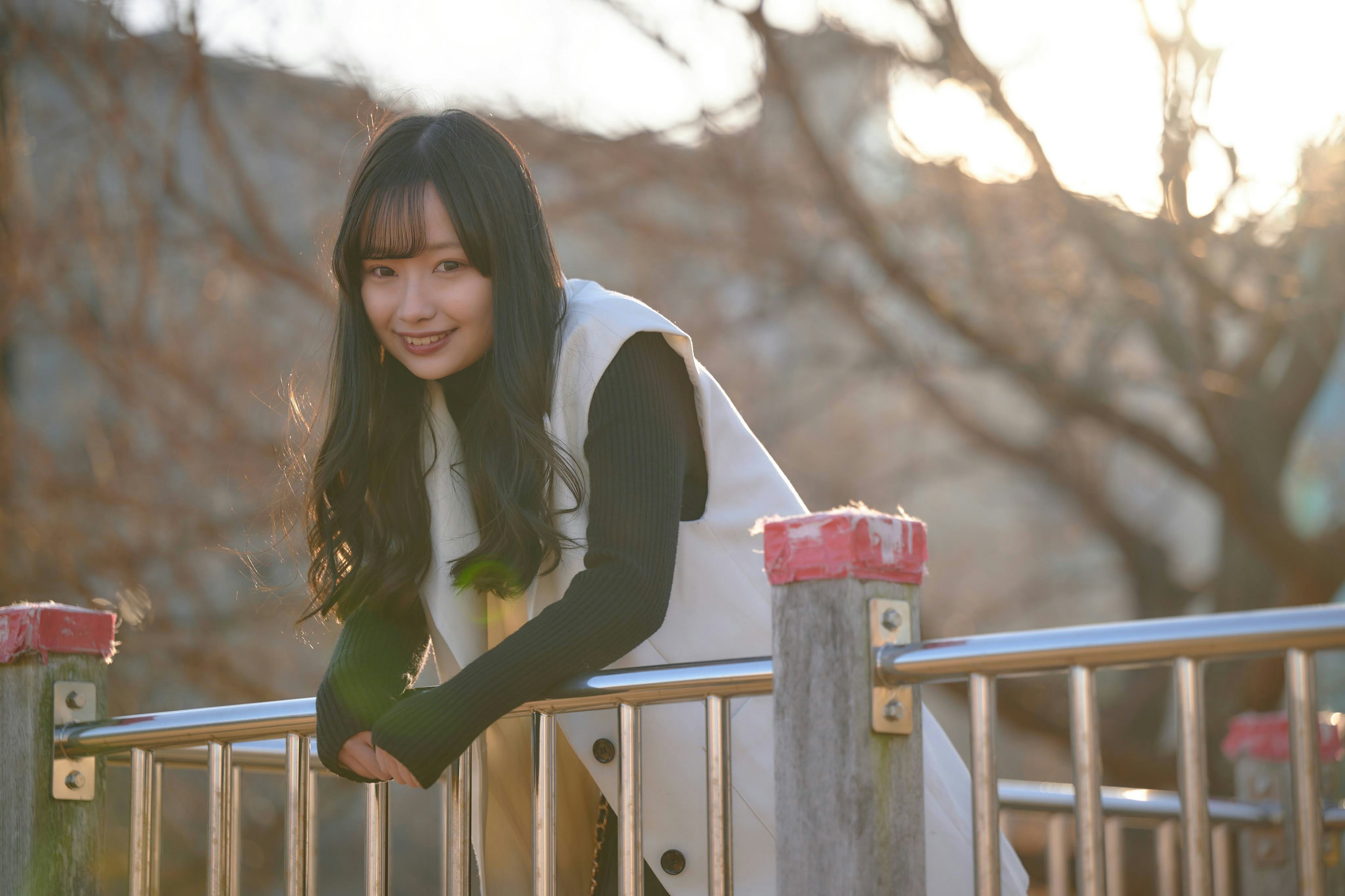 Smiling woman leaning on a park fence with soft lighting