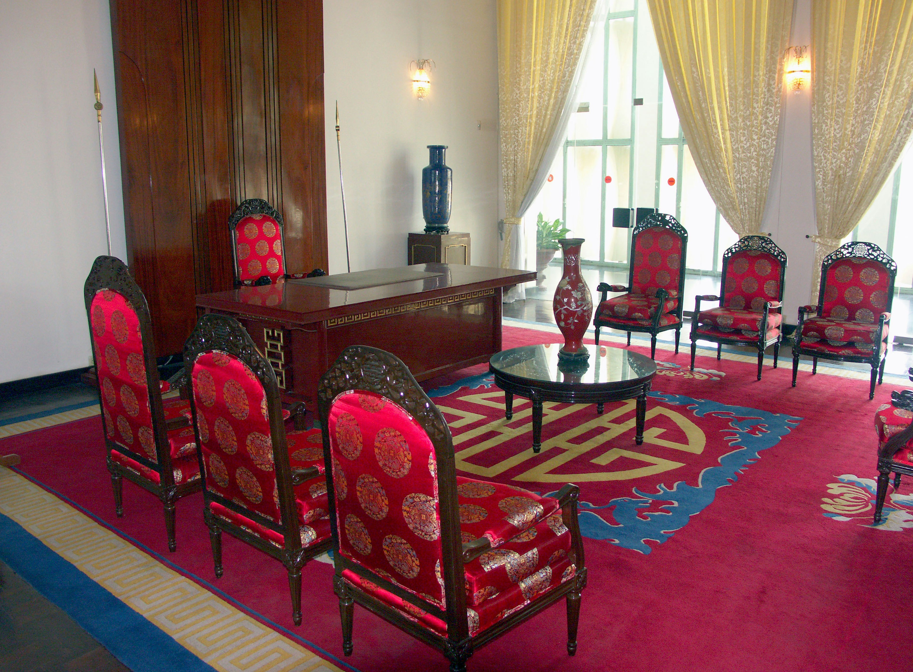 Área de salón con alfombra roja y sillas ornamentadas