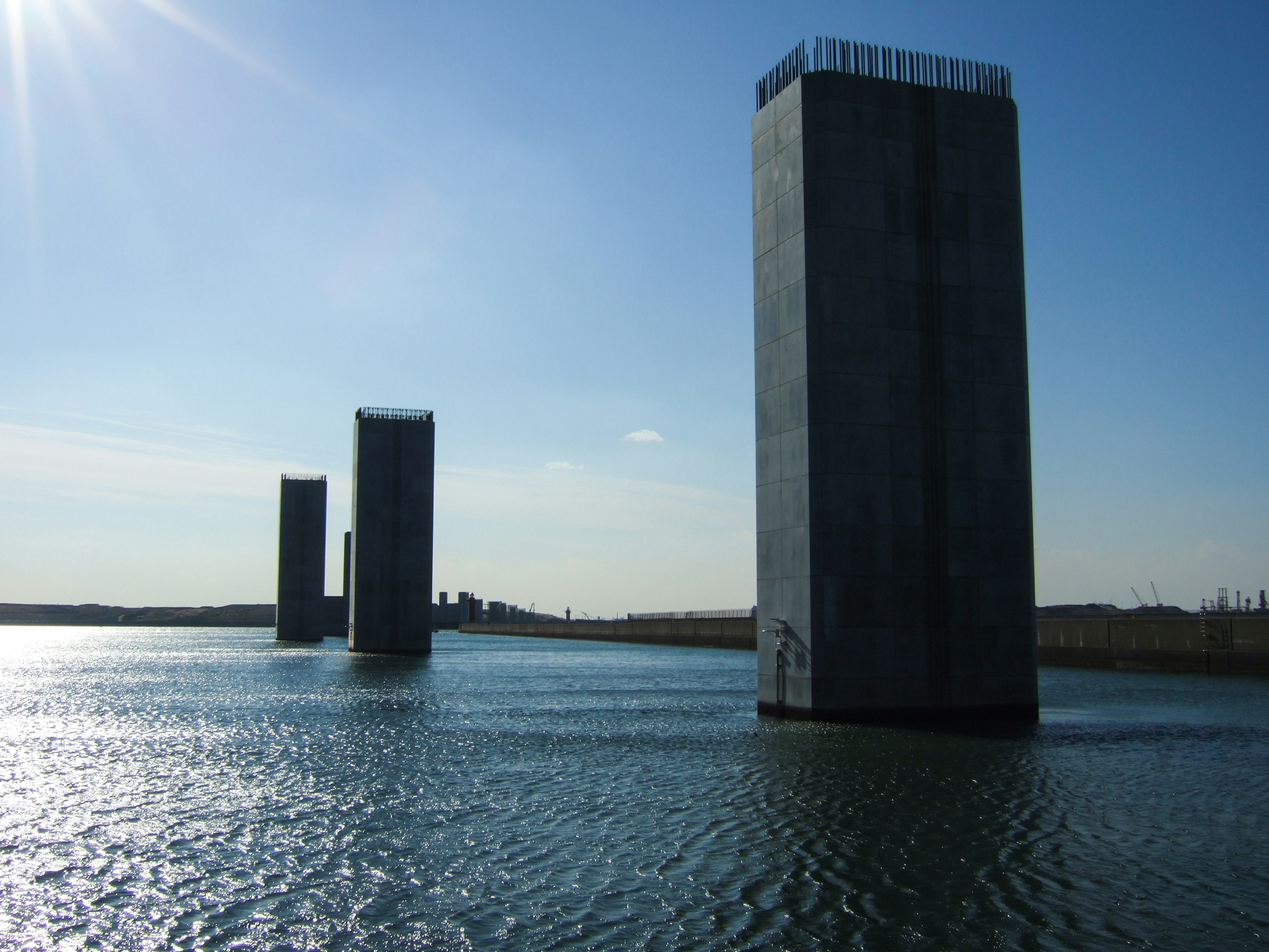 Betonsäulen, die aus dem Wasser unter einem klaren blauen Himmel ragen