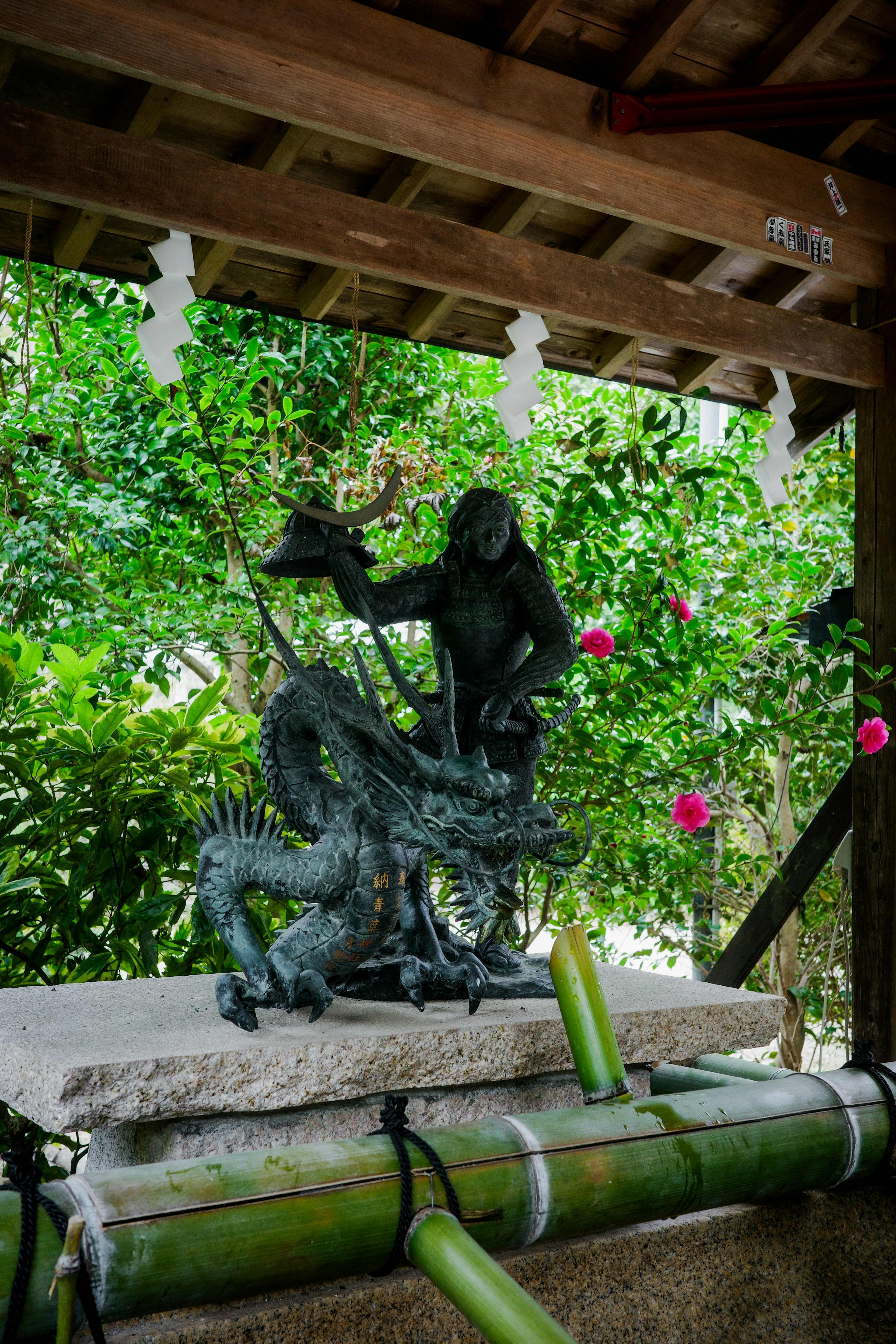 Statue d'une figure brandissant un dragon entourée de verdure