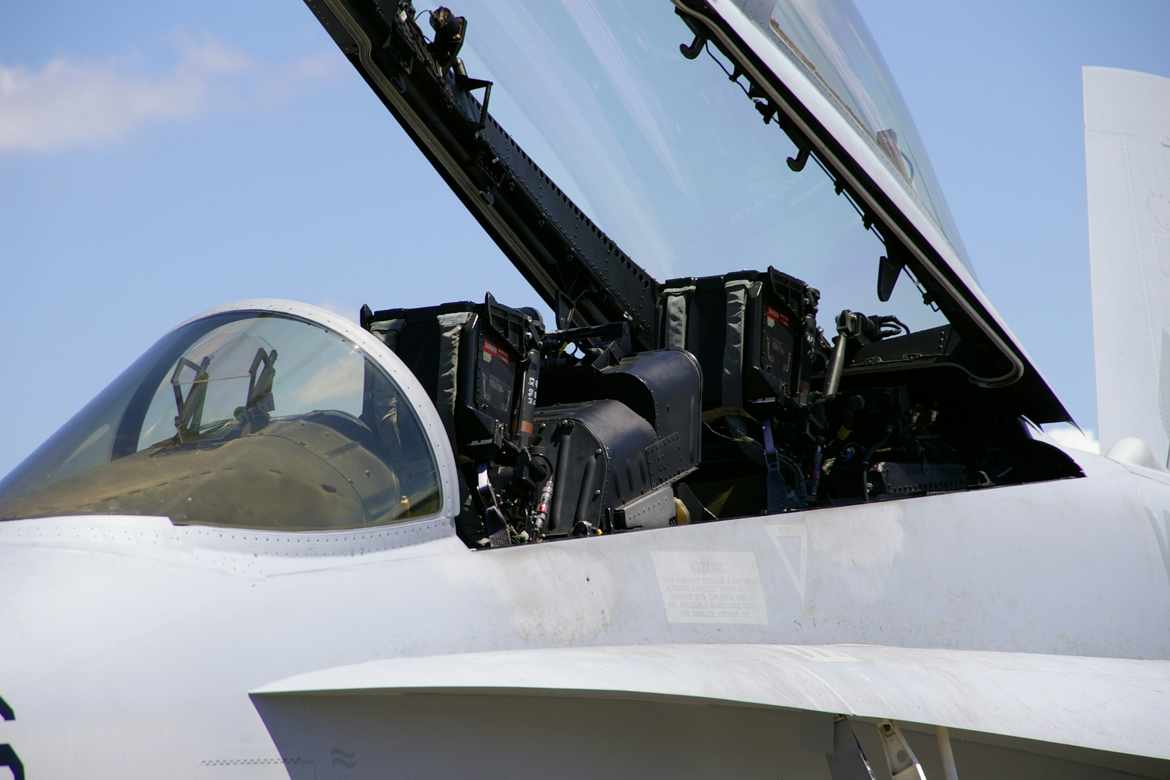 Close-up of a fighter jet with an open canopy revealing internal equipment