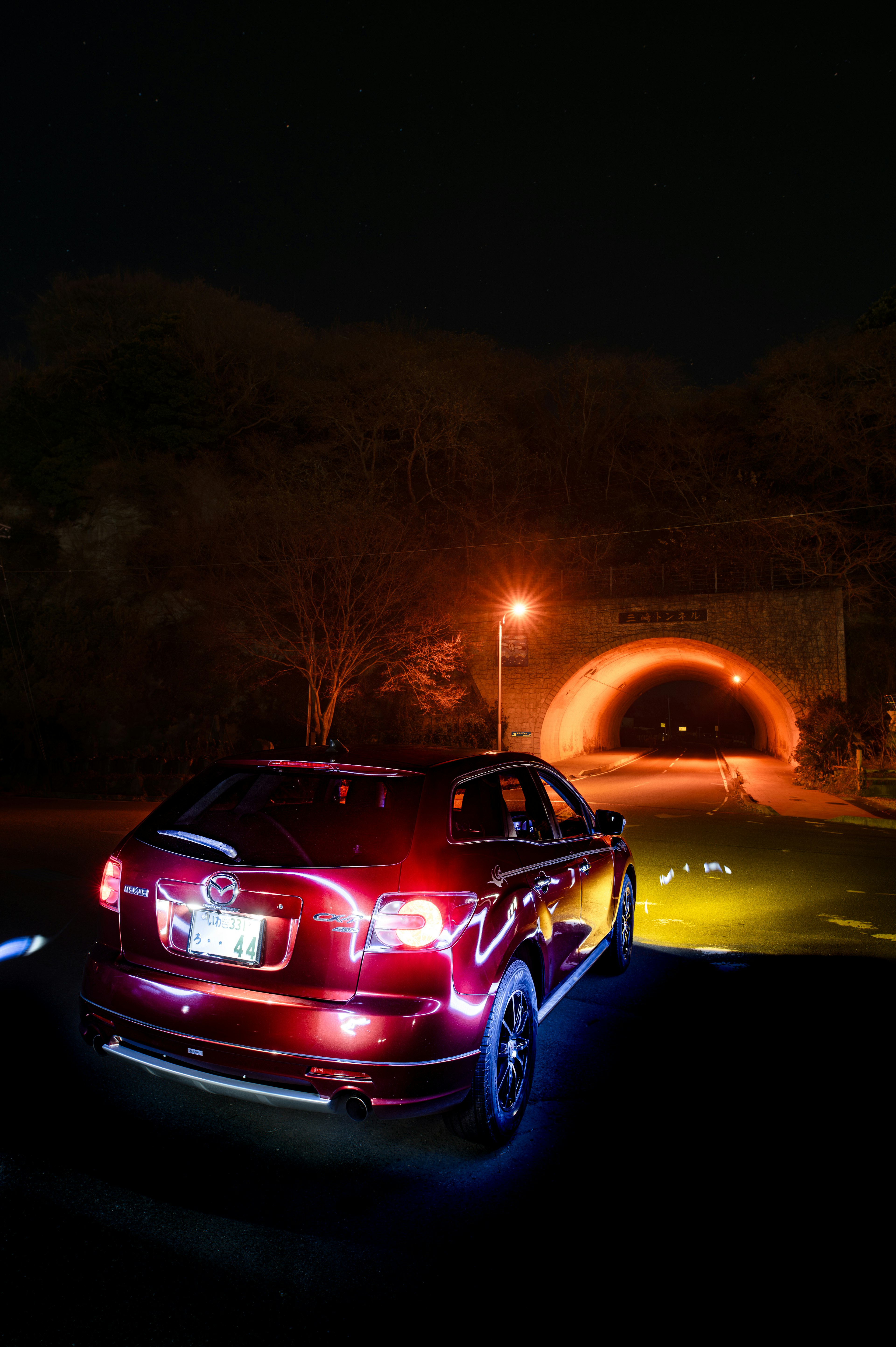 Rotes Auto, das nachts vor einem Tunnel parkt