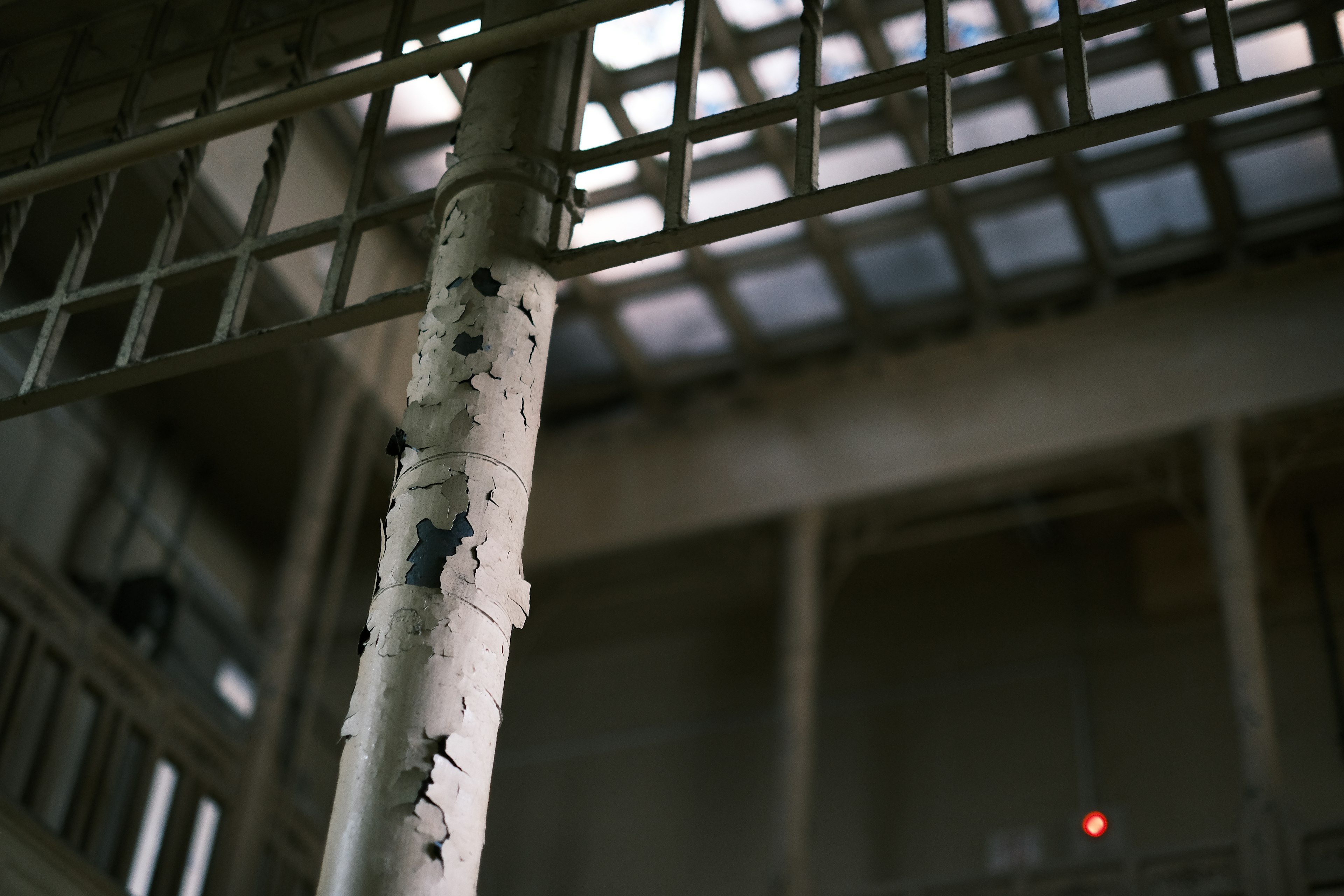 Interior de un edificio antiguo con una columna desconchada y un techo enrejado