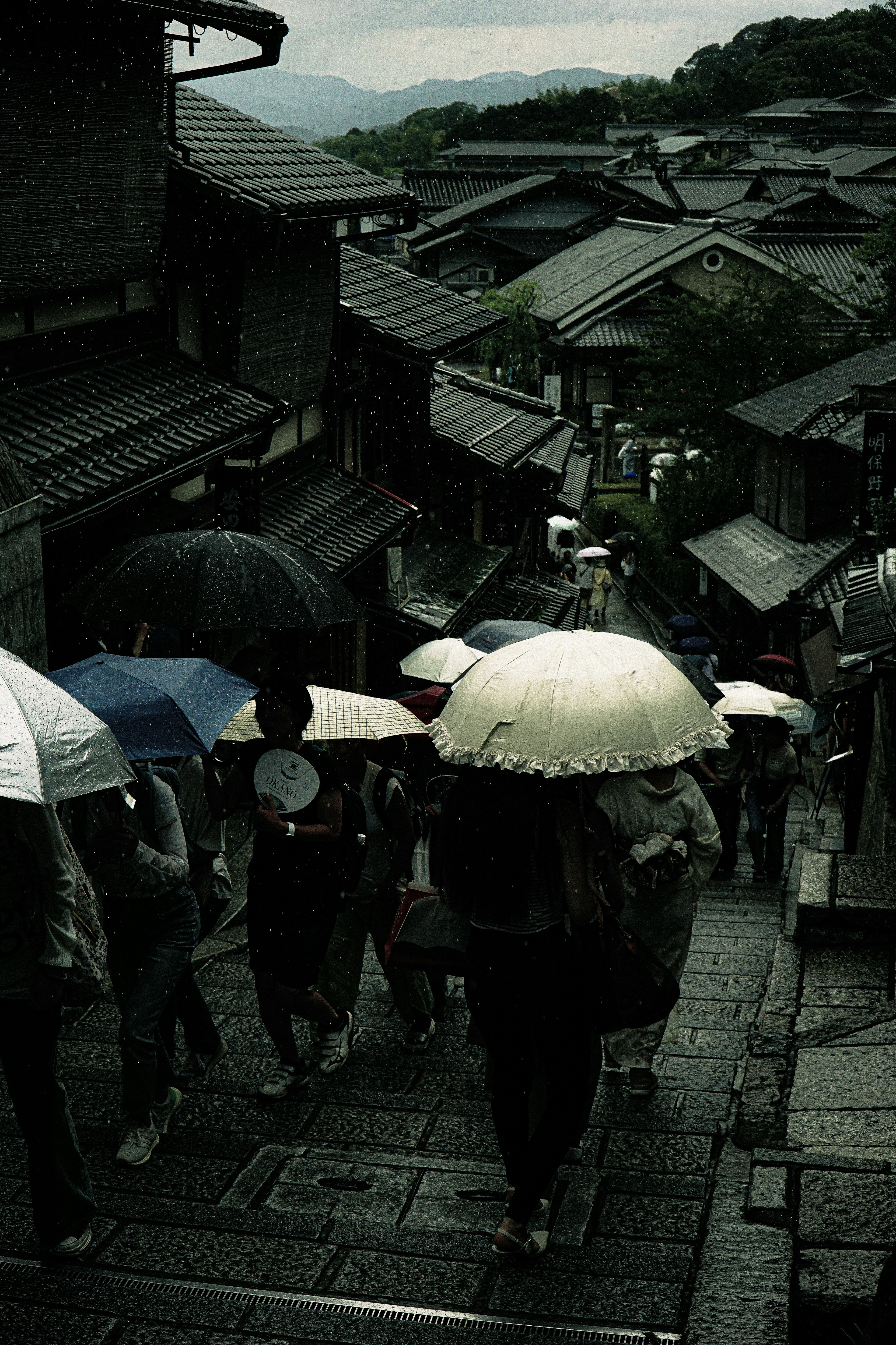 Orang-orang berjalan di bawah hujan dengan payung di jalan Kyoto