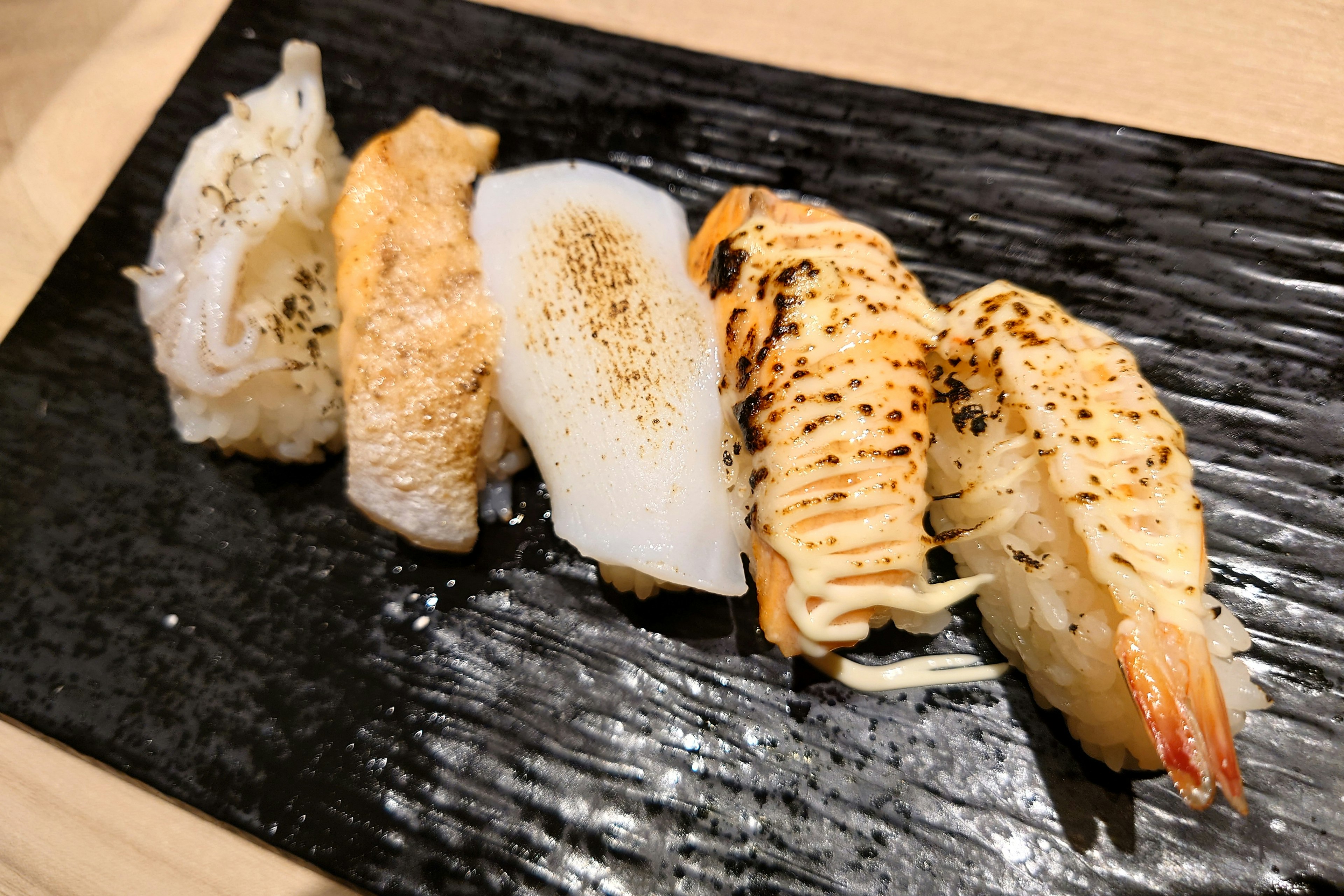 黑色盤子上的 assorted grilled sushi