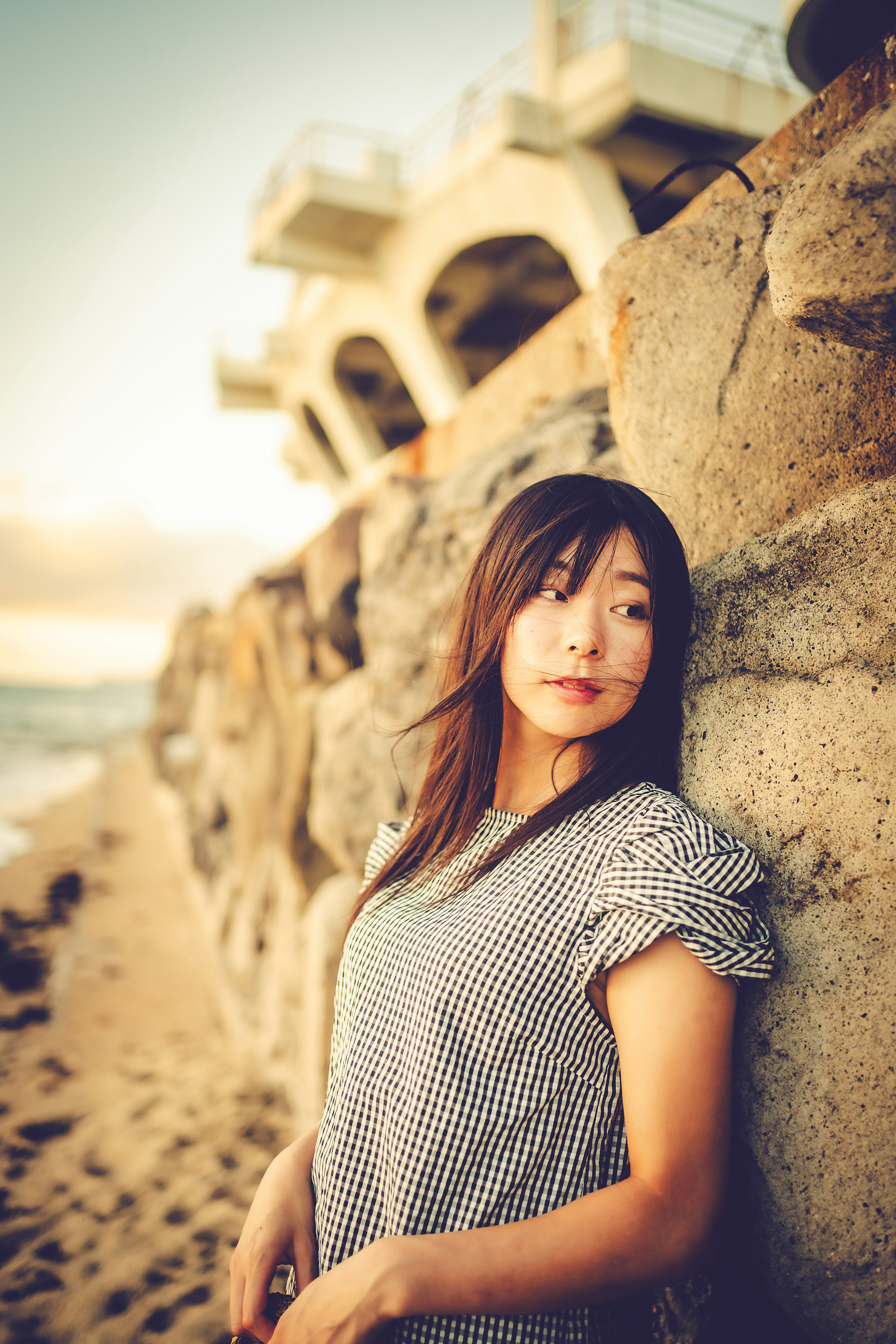 Retrato de una mujer apoyada en rocas costeras luz suave del atardecer