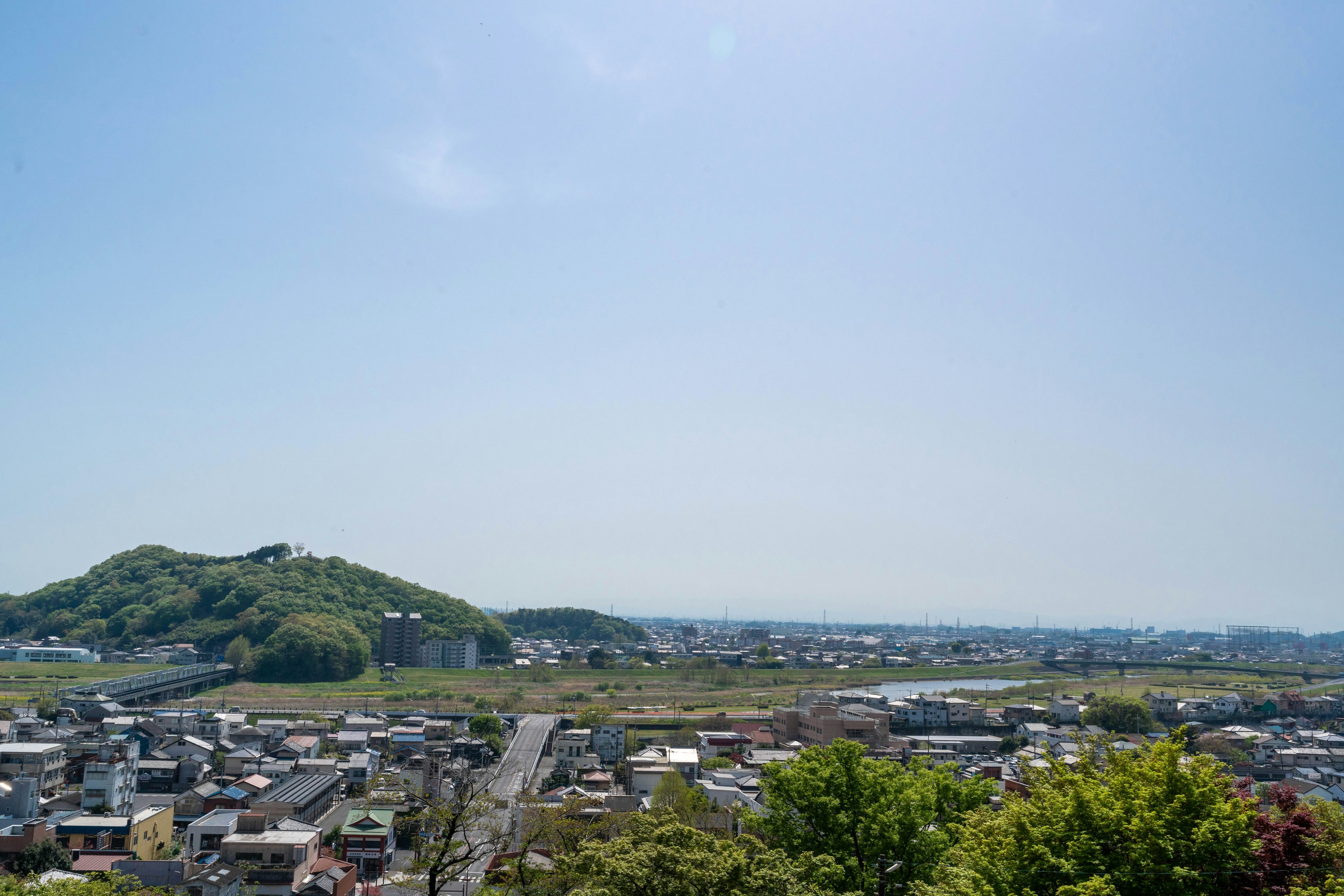 Vista panoramica di una città sotto un cielo blu chiaro con colline verdi