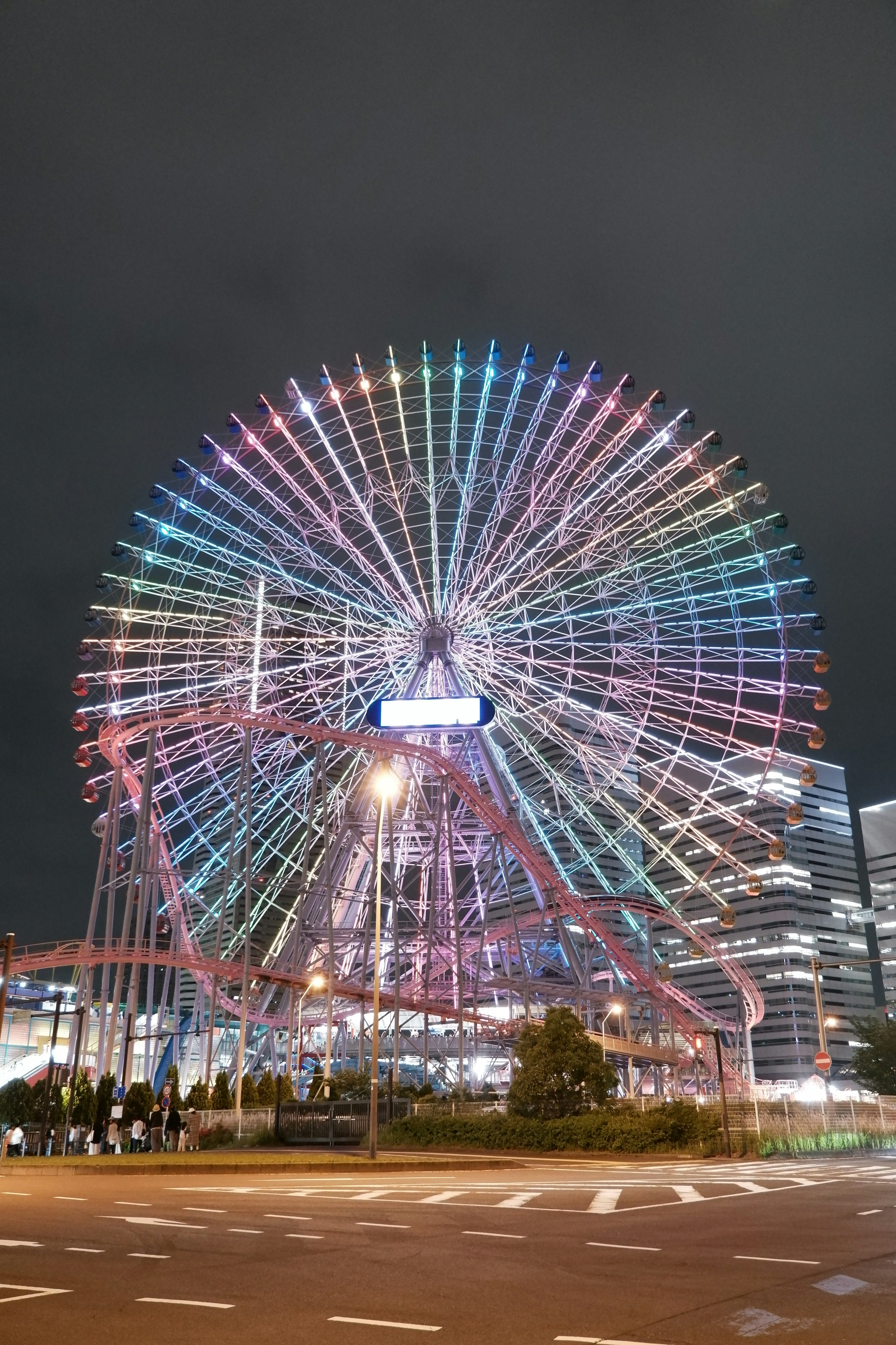 Grande roue colorée illuminée la nuit entourée de paysages urbains