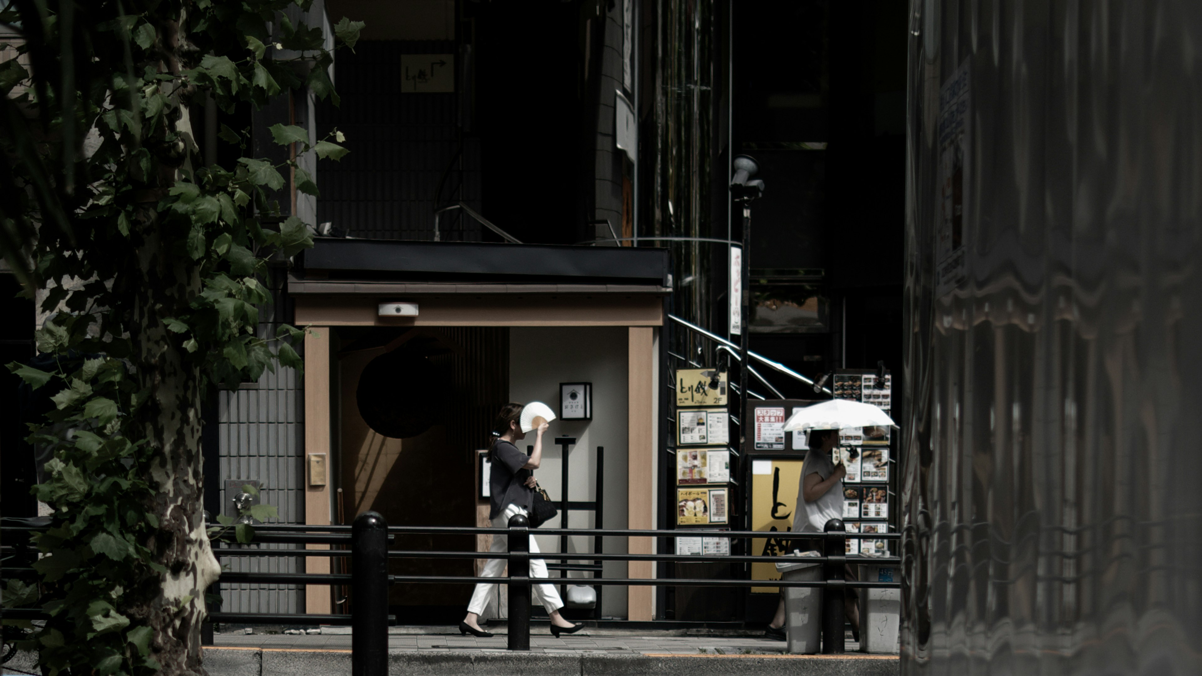 A person standing in a quiet urban street holding an umbrella