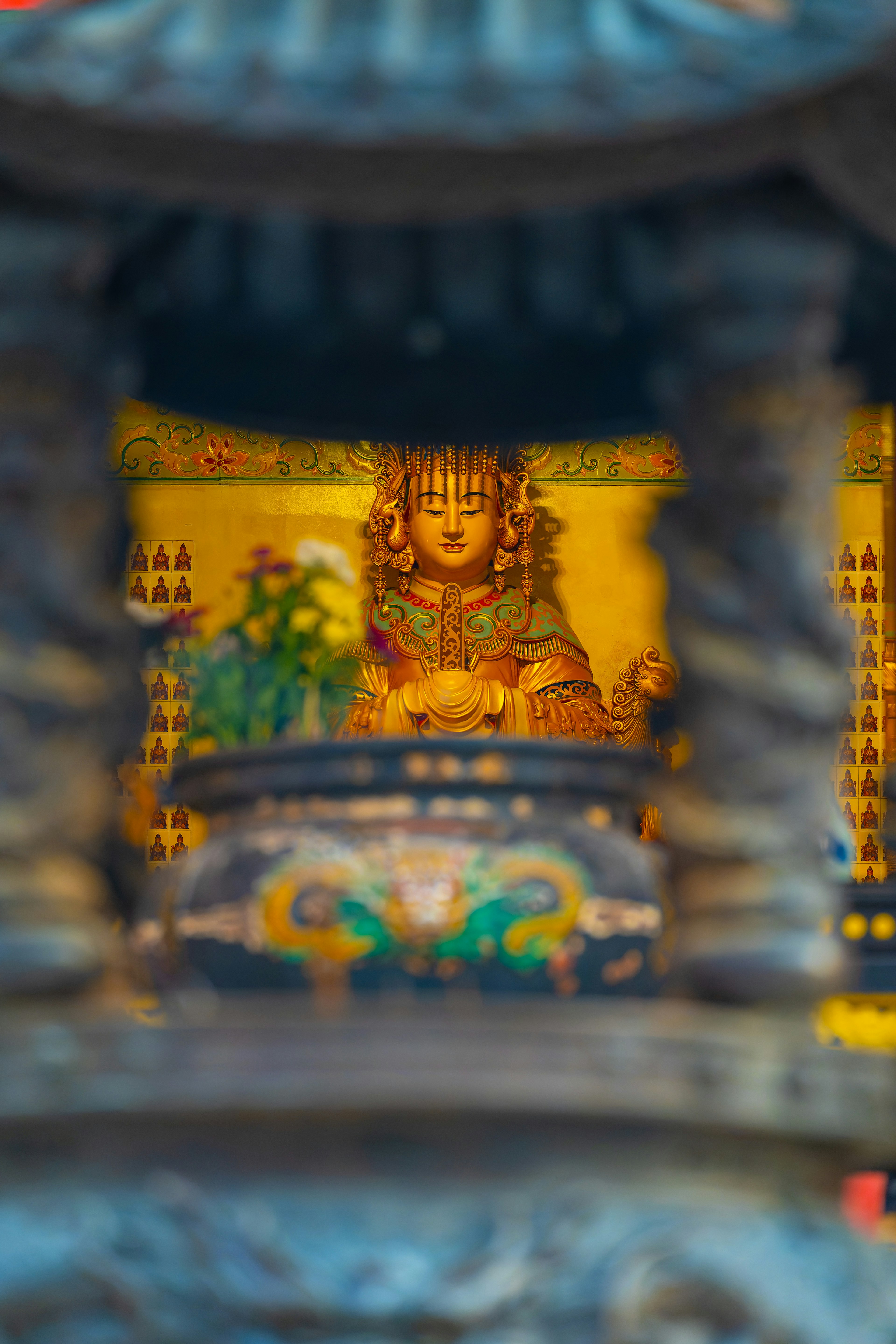 Stone lantern framing a golden statue inside a temple