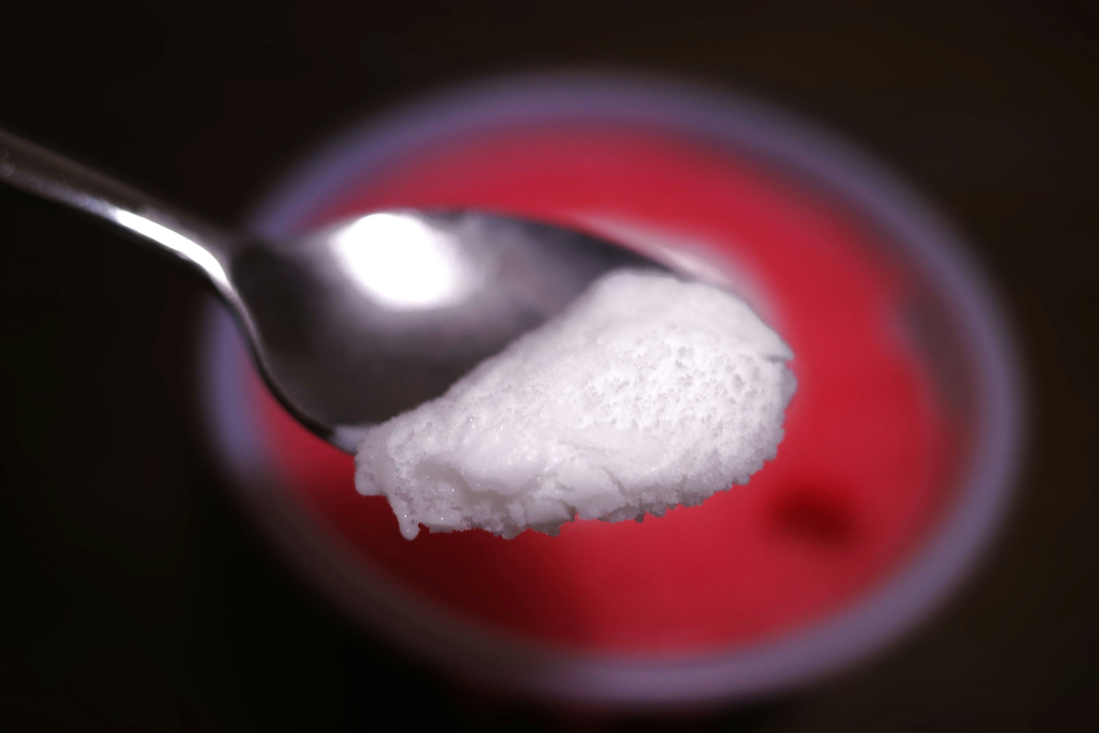 A spoonful of white cream above a red dessert