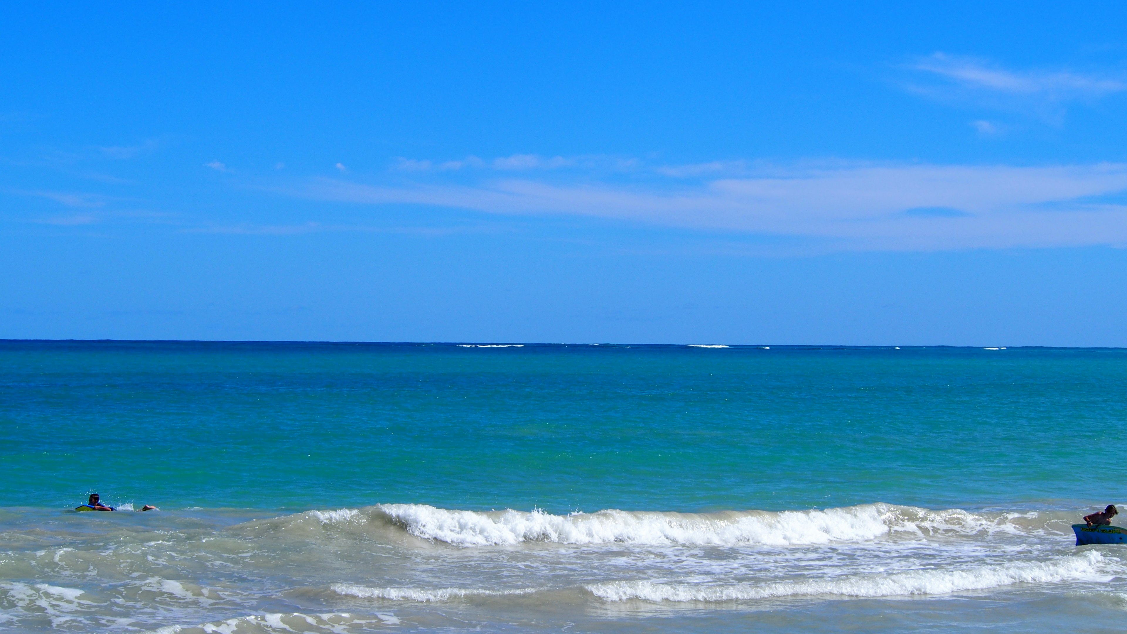 Strandszene mit blauem Wasser und weißen Wellen