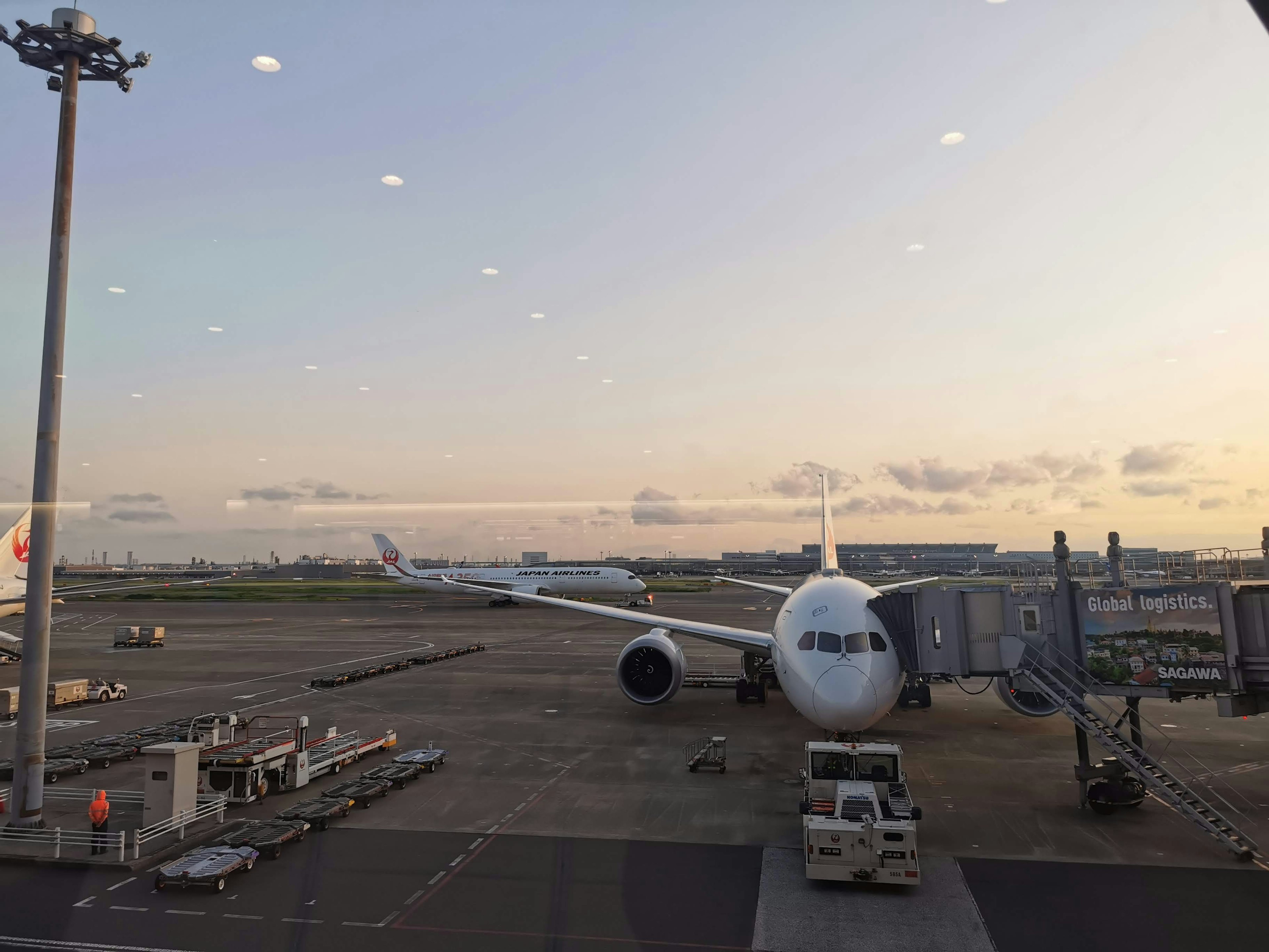 空港の滑走路に停まっている白い飛行機と夕焼けの空