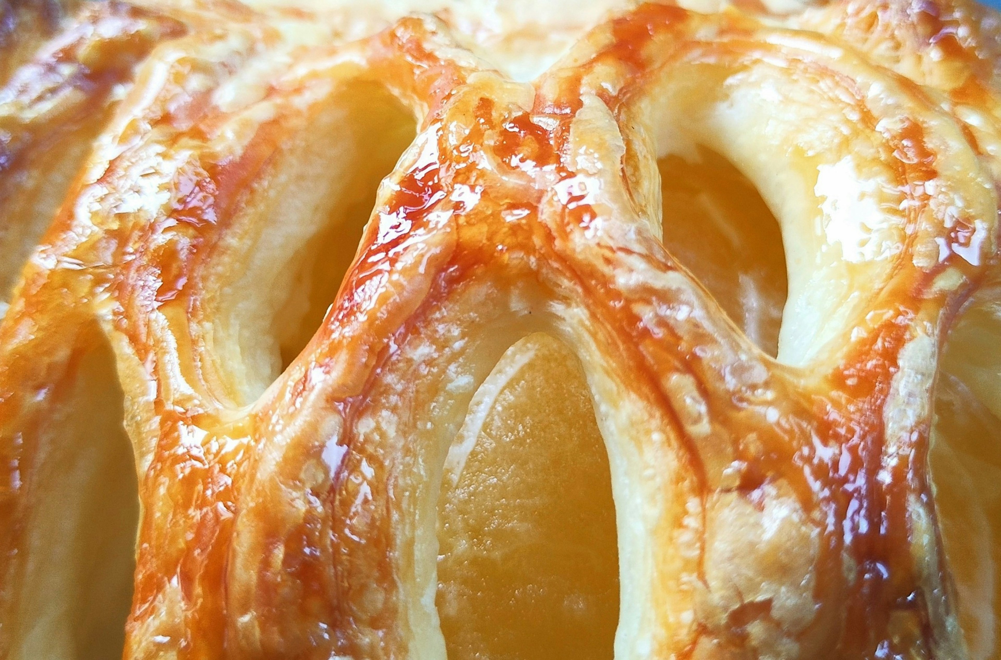 Close-up of a flaky pastry crust with golden-brown layers and visible fruit filling