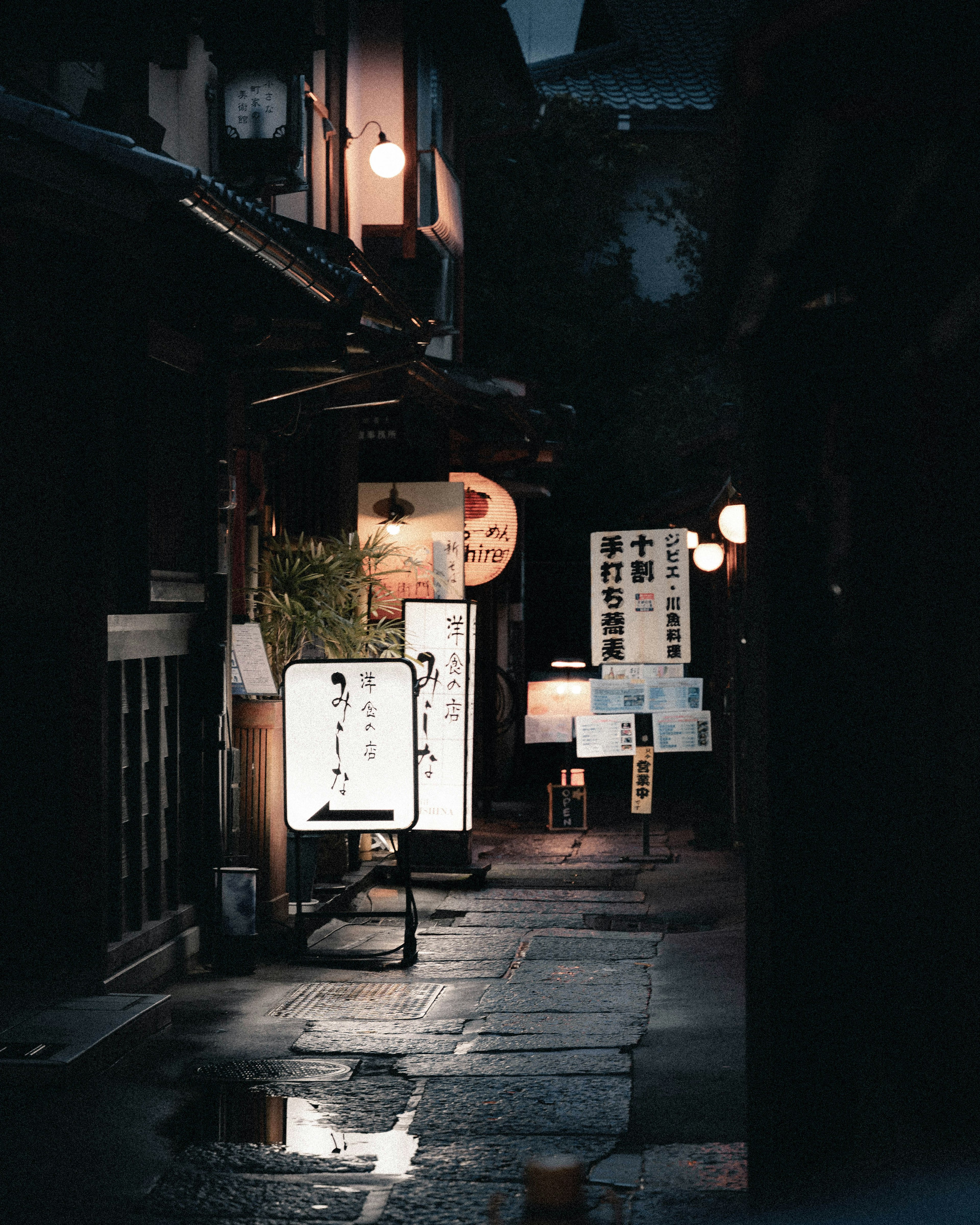 A narrow alley at night illuminated by soft lights and signs