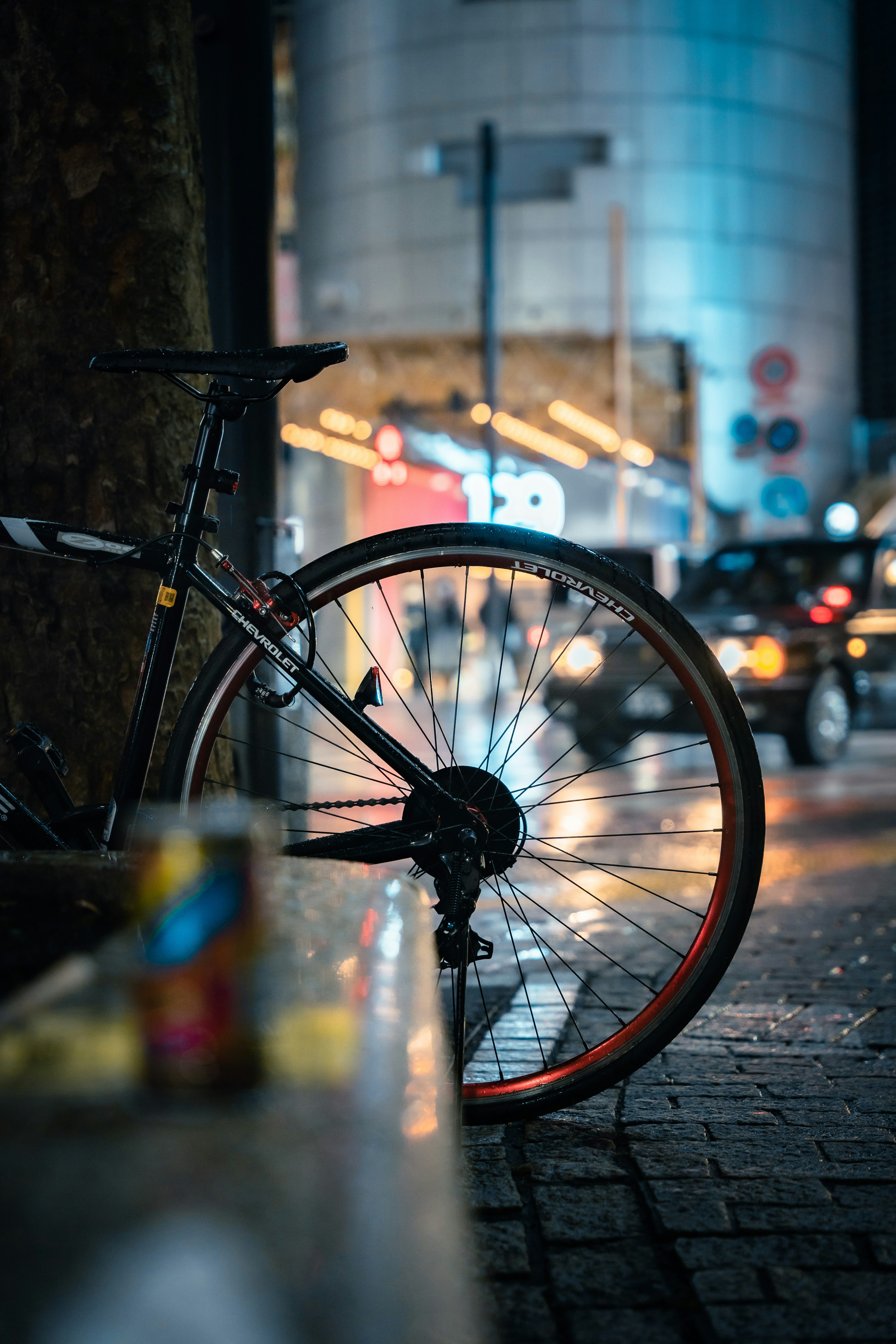 Night city scene with a bicycle wheel and wet pavement