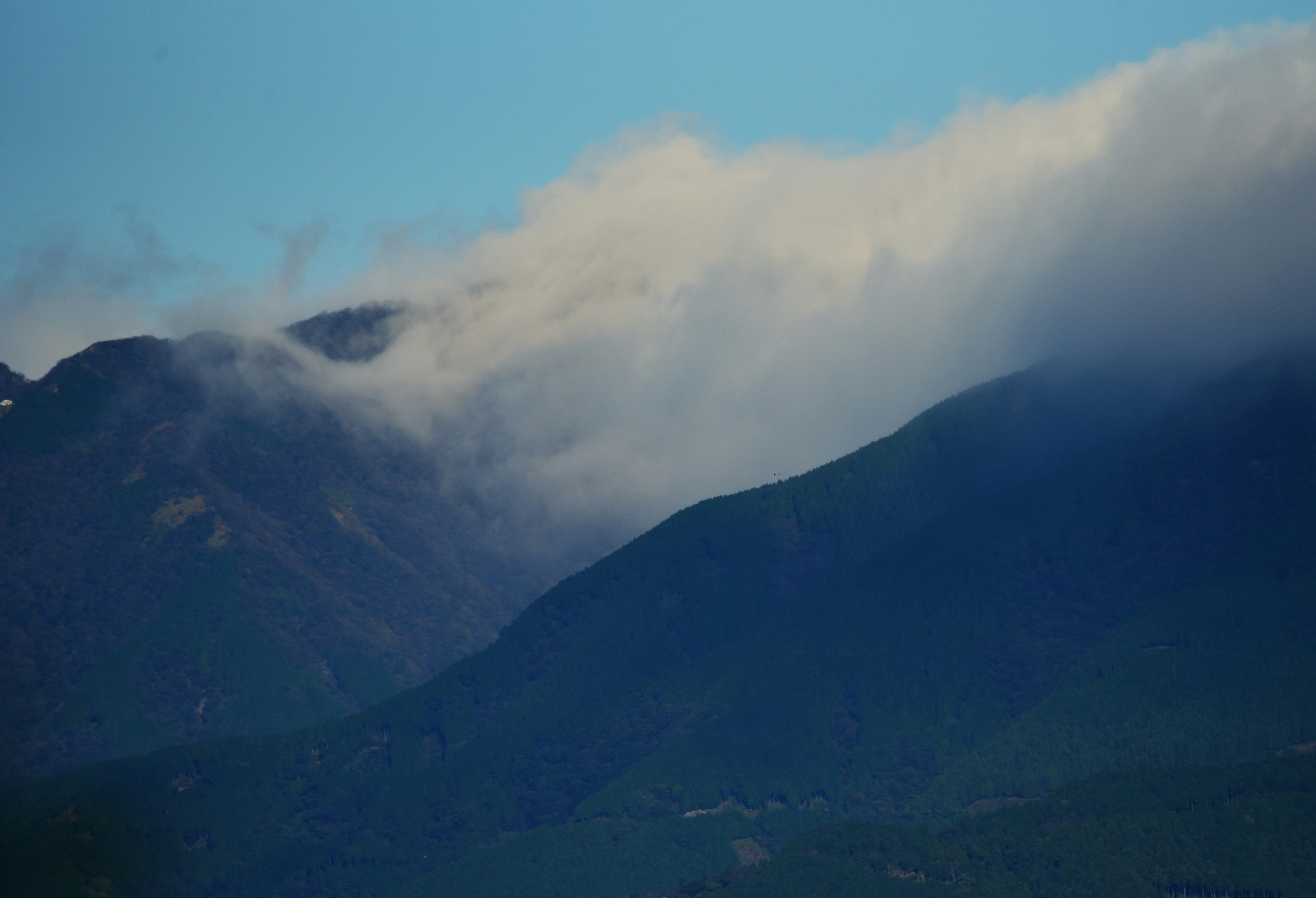 Gunung yang sebagian tertutup awan di bawah langit biru