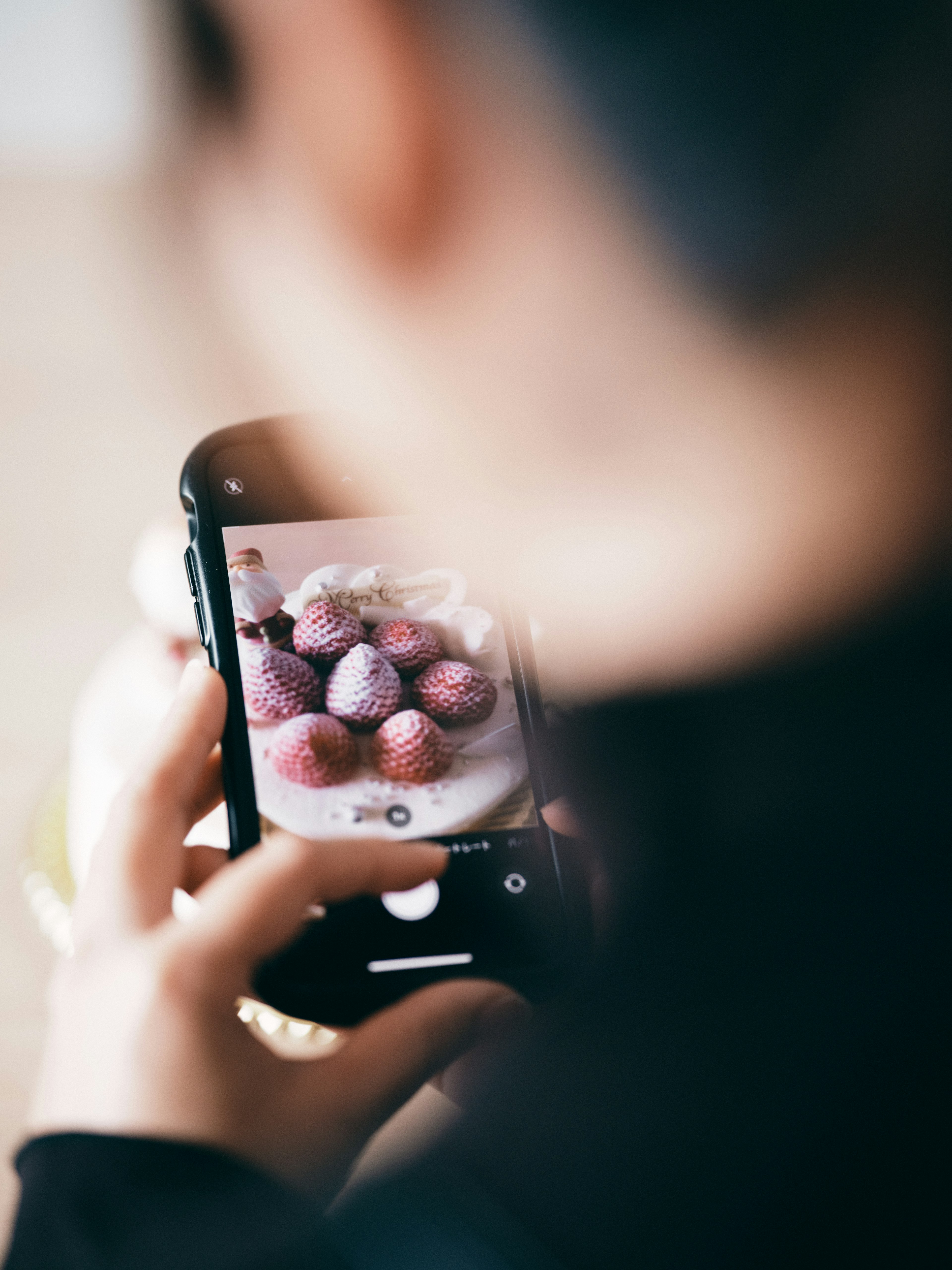 Seorang wanita mengambil foto kue berwarna-warni dengan ponselnya