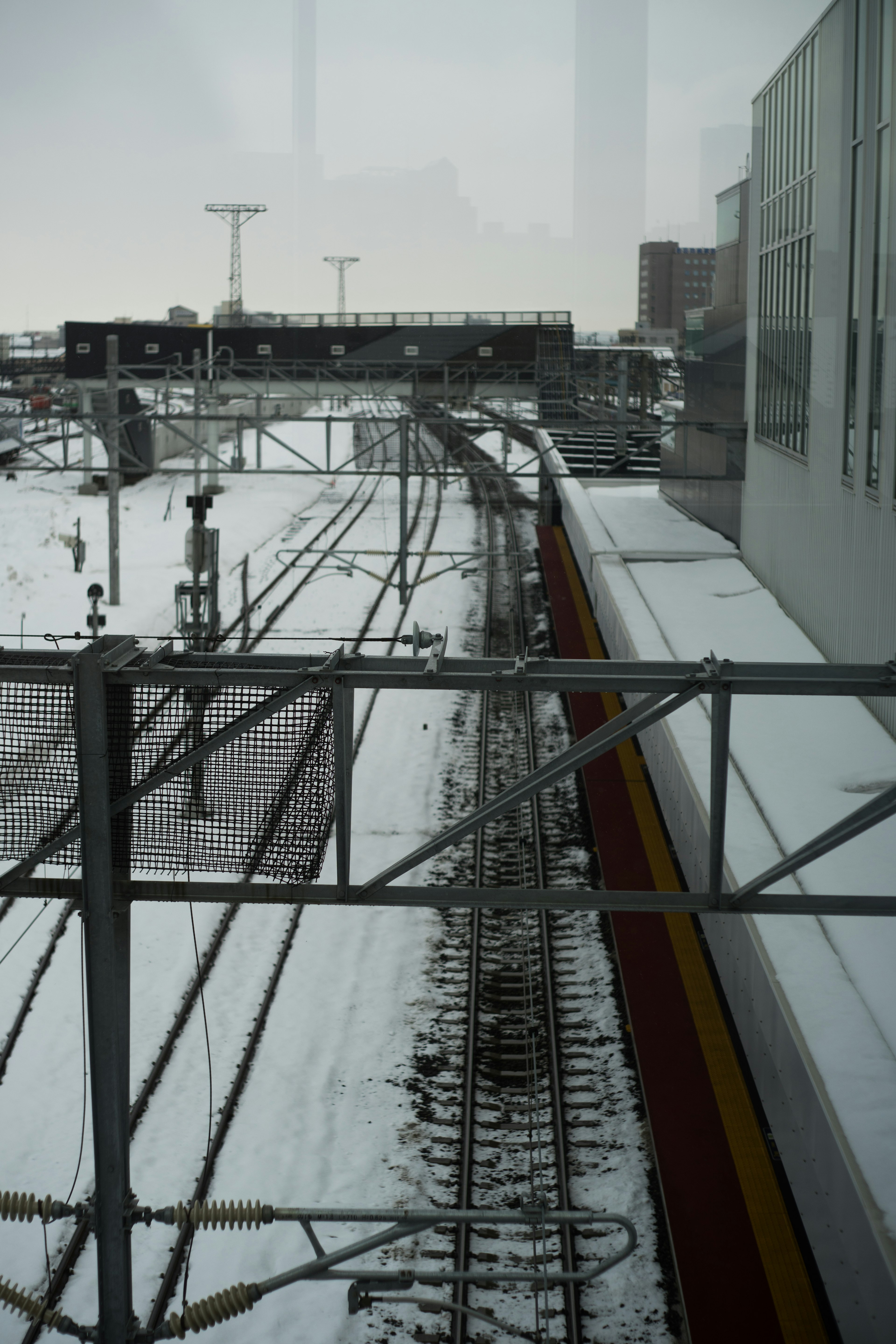 雪に覆われた鉄道の線路と架線が見える冬の風景