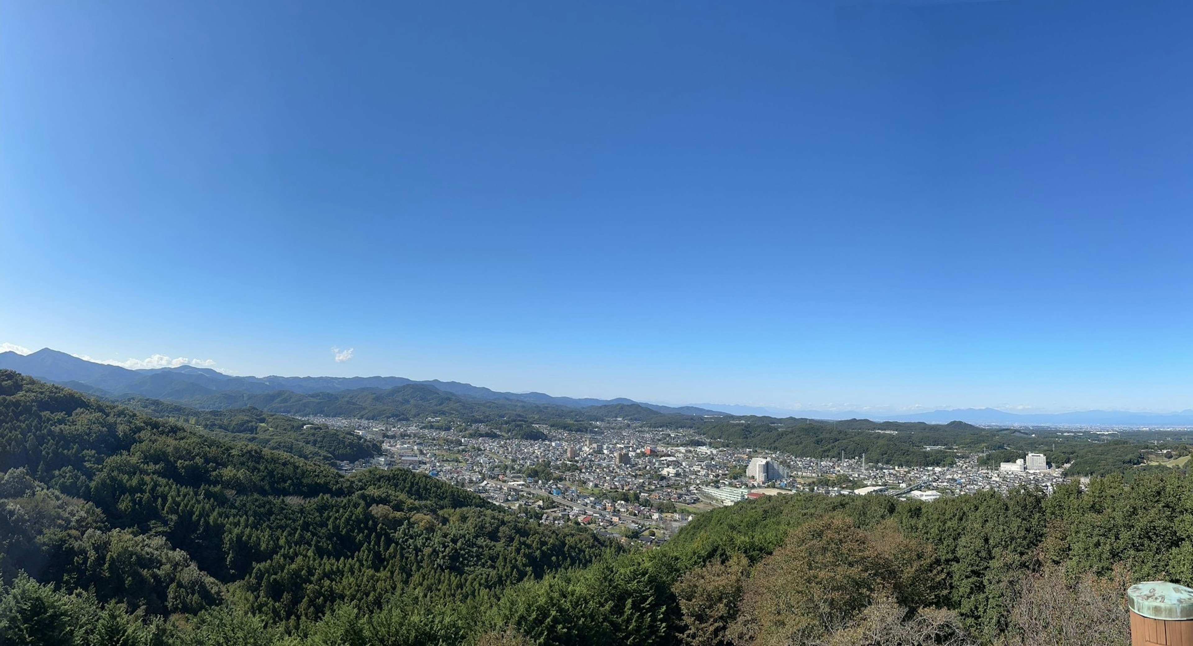 广阔城市的全景视图，背景为蓝天和山脉