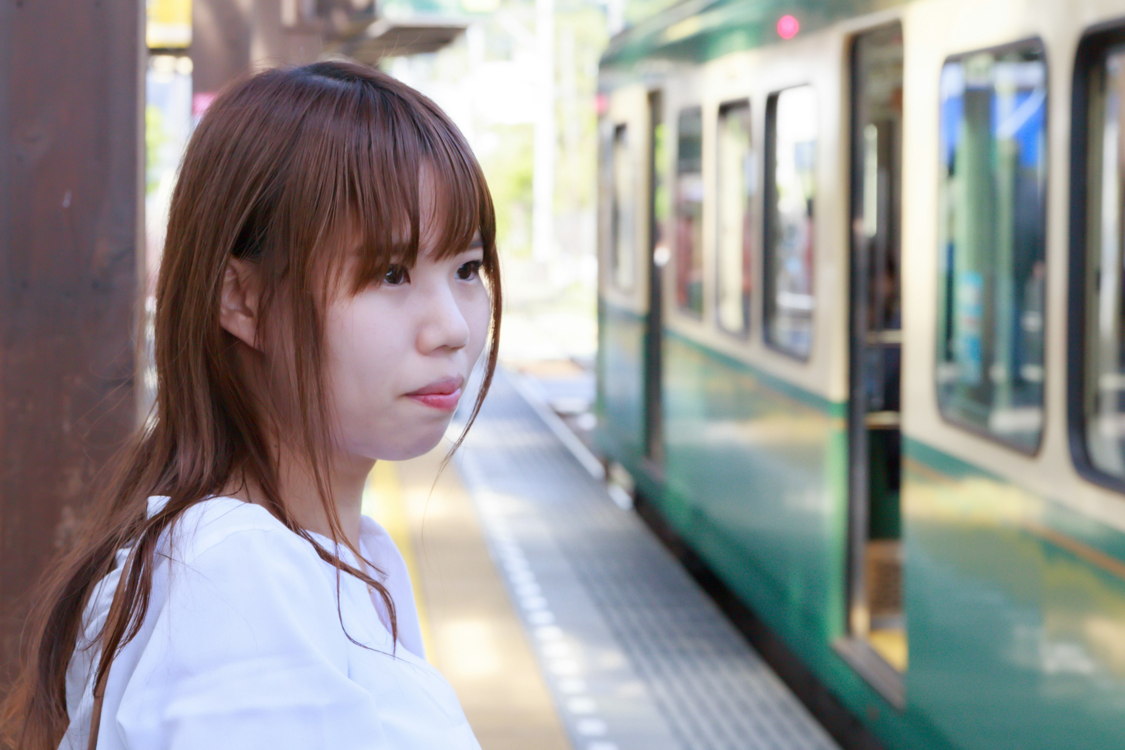 Une femme attendant à une gare près d'un train vert