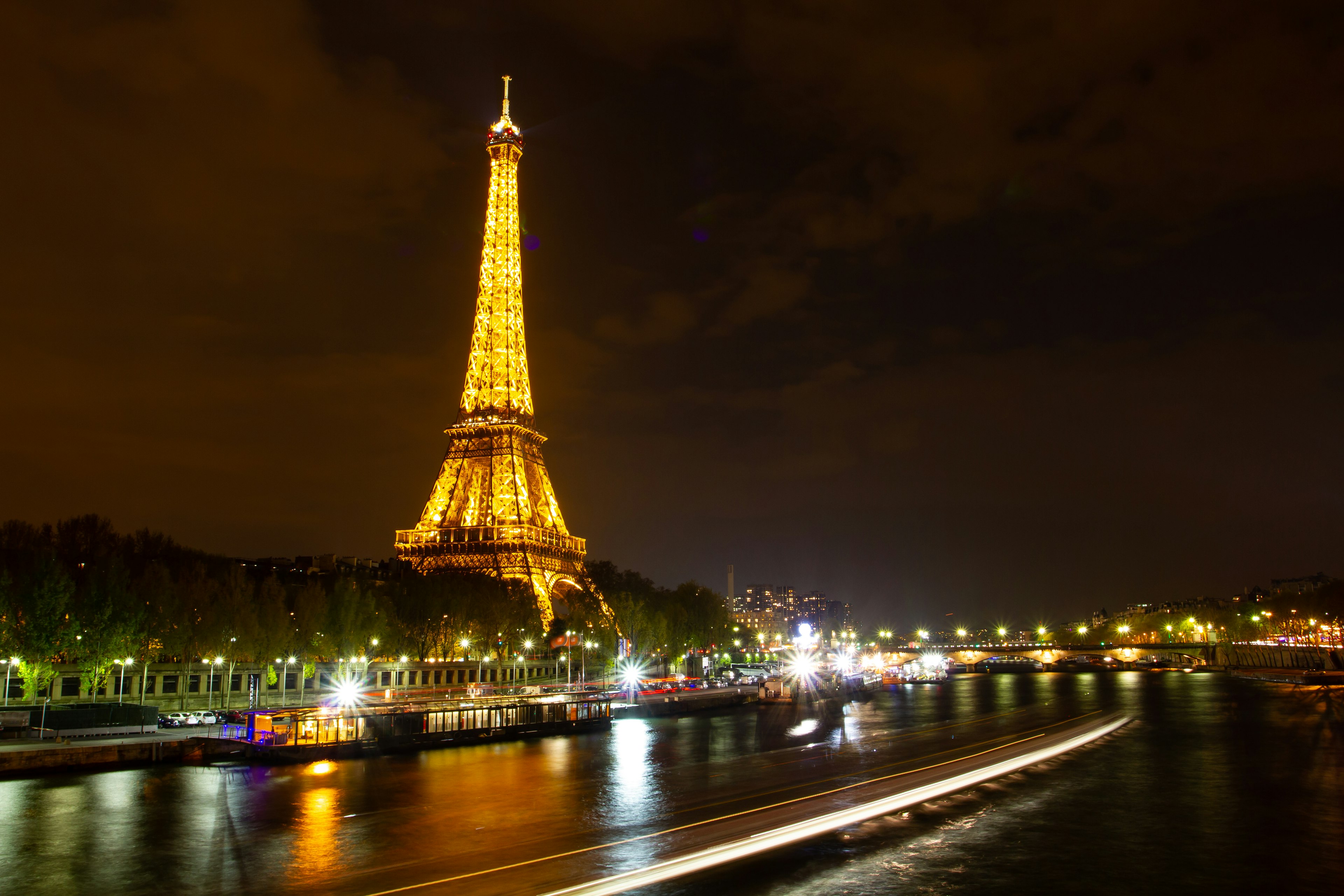 Menara Eiffel yang diterangi di malam hari di tepi Sungai Seine