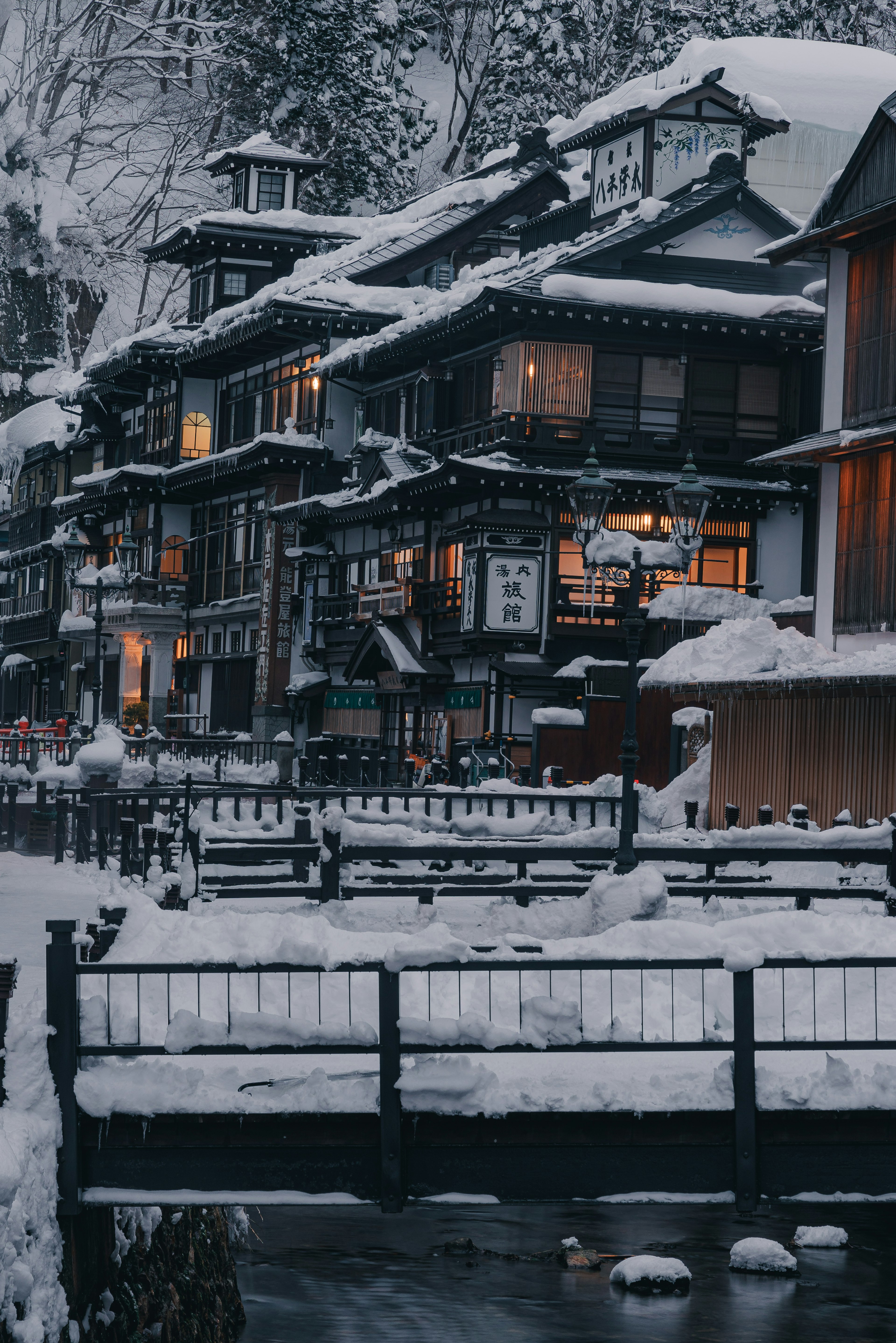 Traditionelle japanische Unterkunft, die mit Schnee bedeckt ist, mit einem Bach