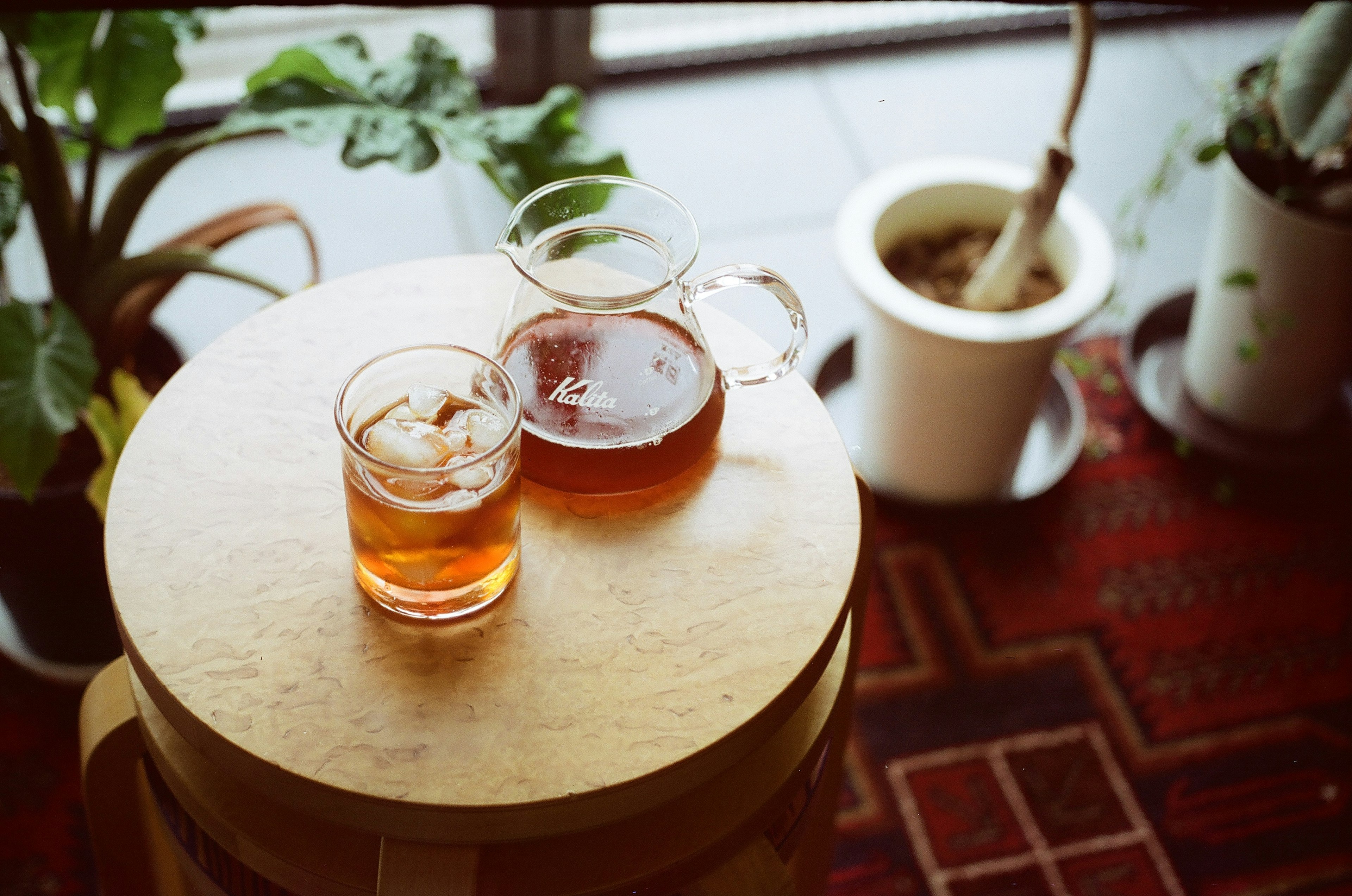 A wooden table featuring a glass of iced tea and a glass of hot tea